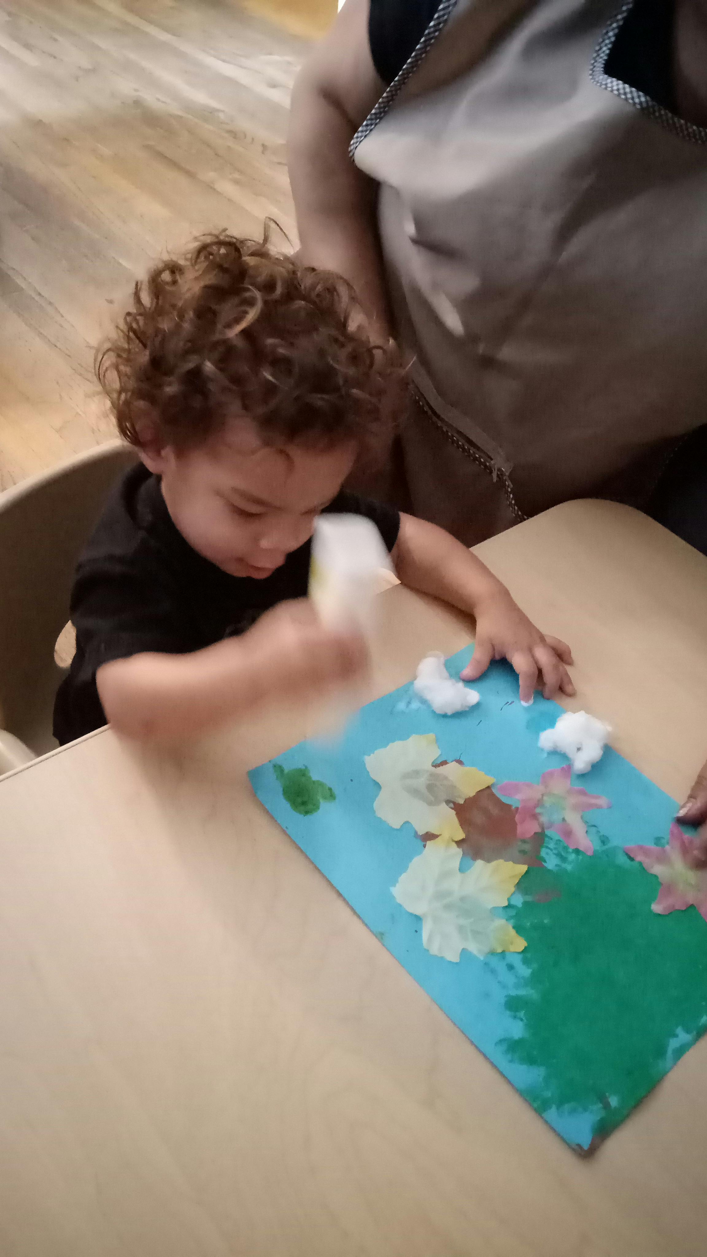 Child creating art with cotton balls and paint