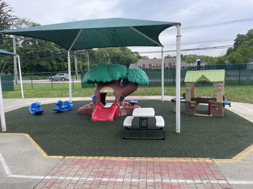 Playground area with shade canopy, tree-shaped slide, ride-on toys, and picnic table