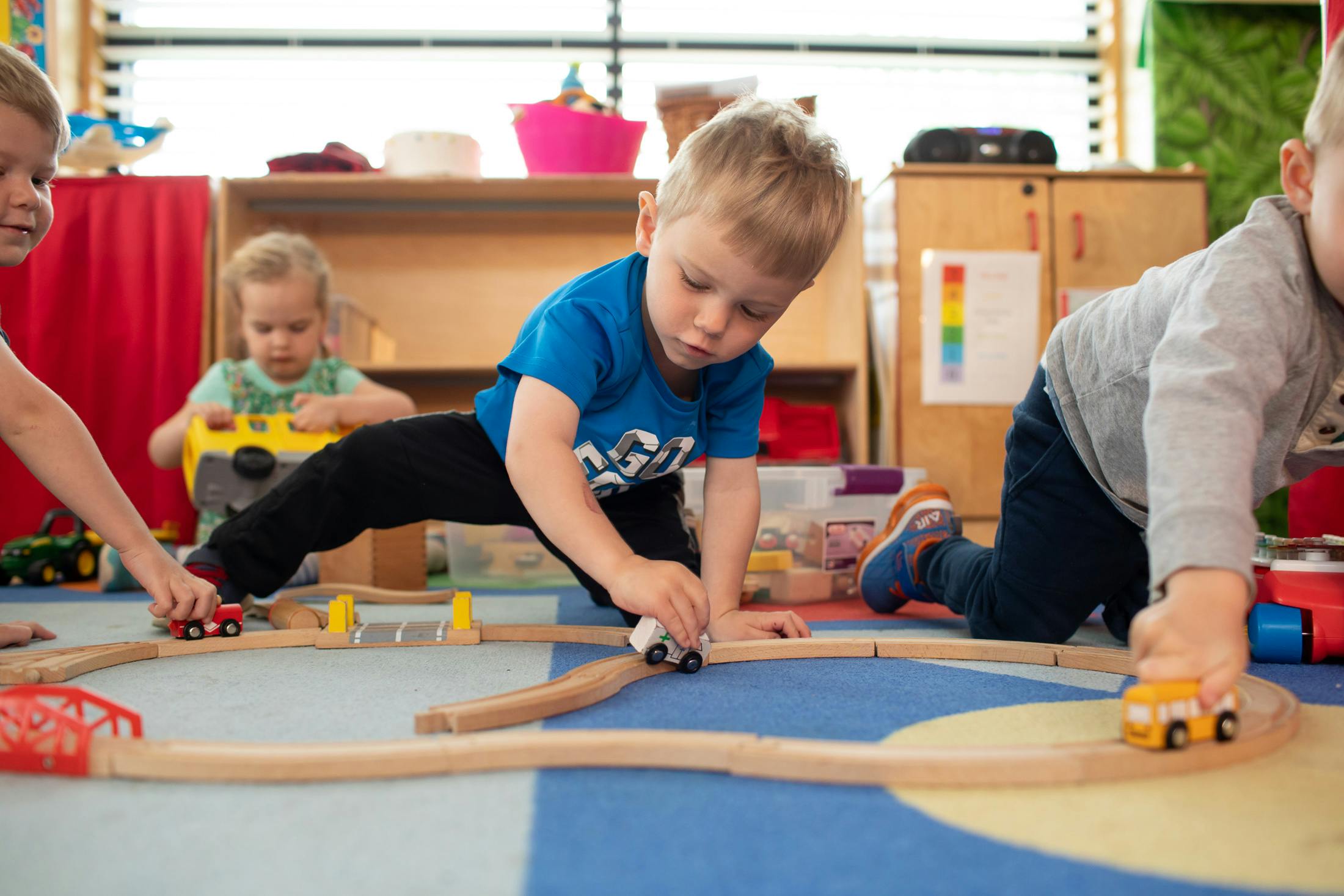 Children playing with toy cars on a wooden train track
