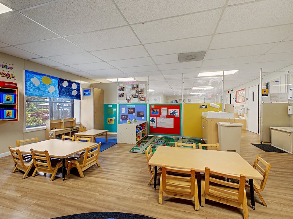 Classroom with child-sized tables and chairs, play kitchen, and colorful artwork