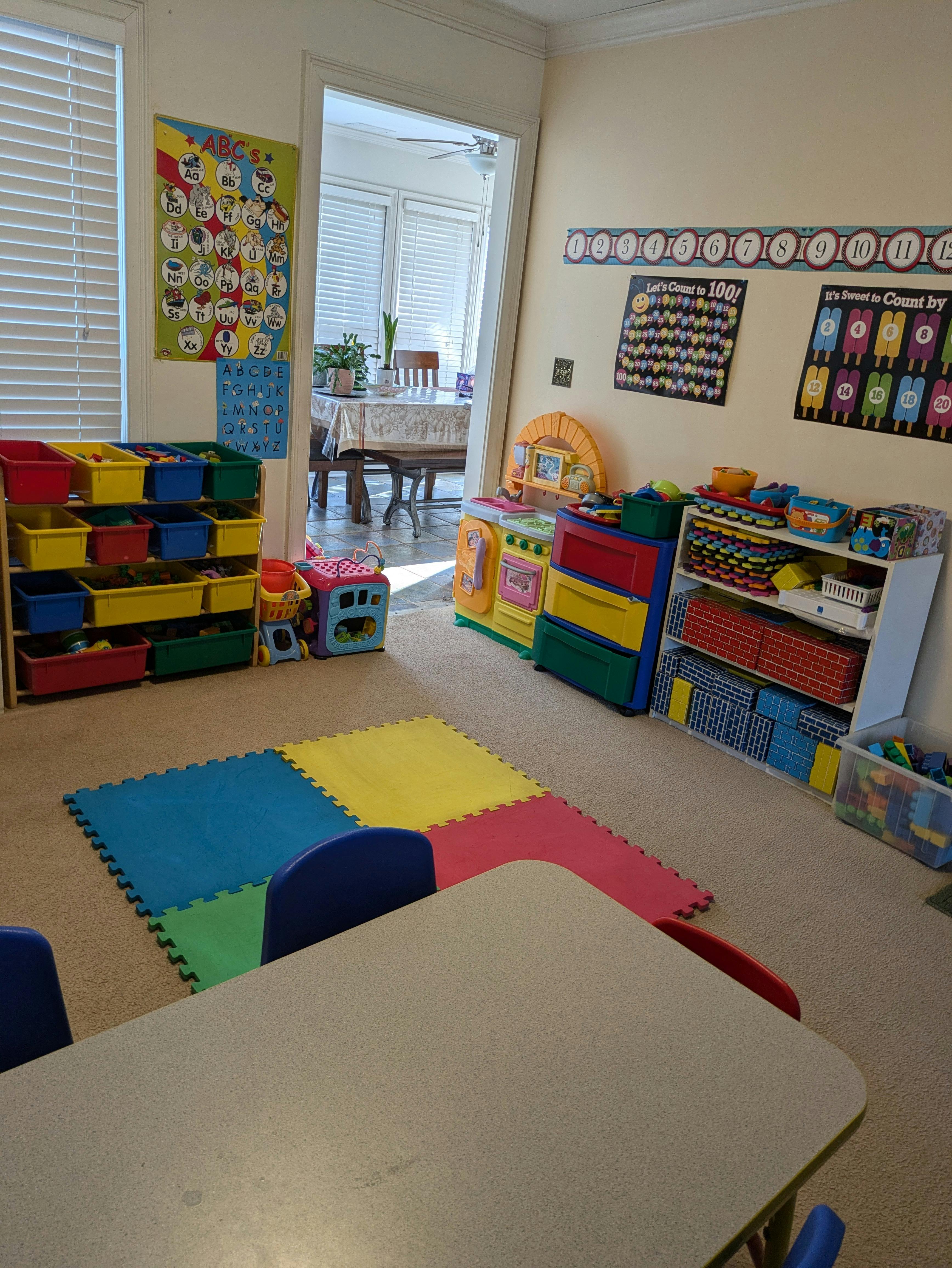 Playroom with educational posters, toy storage shelves, and colorful floor mats