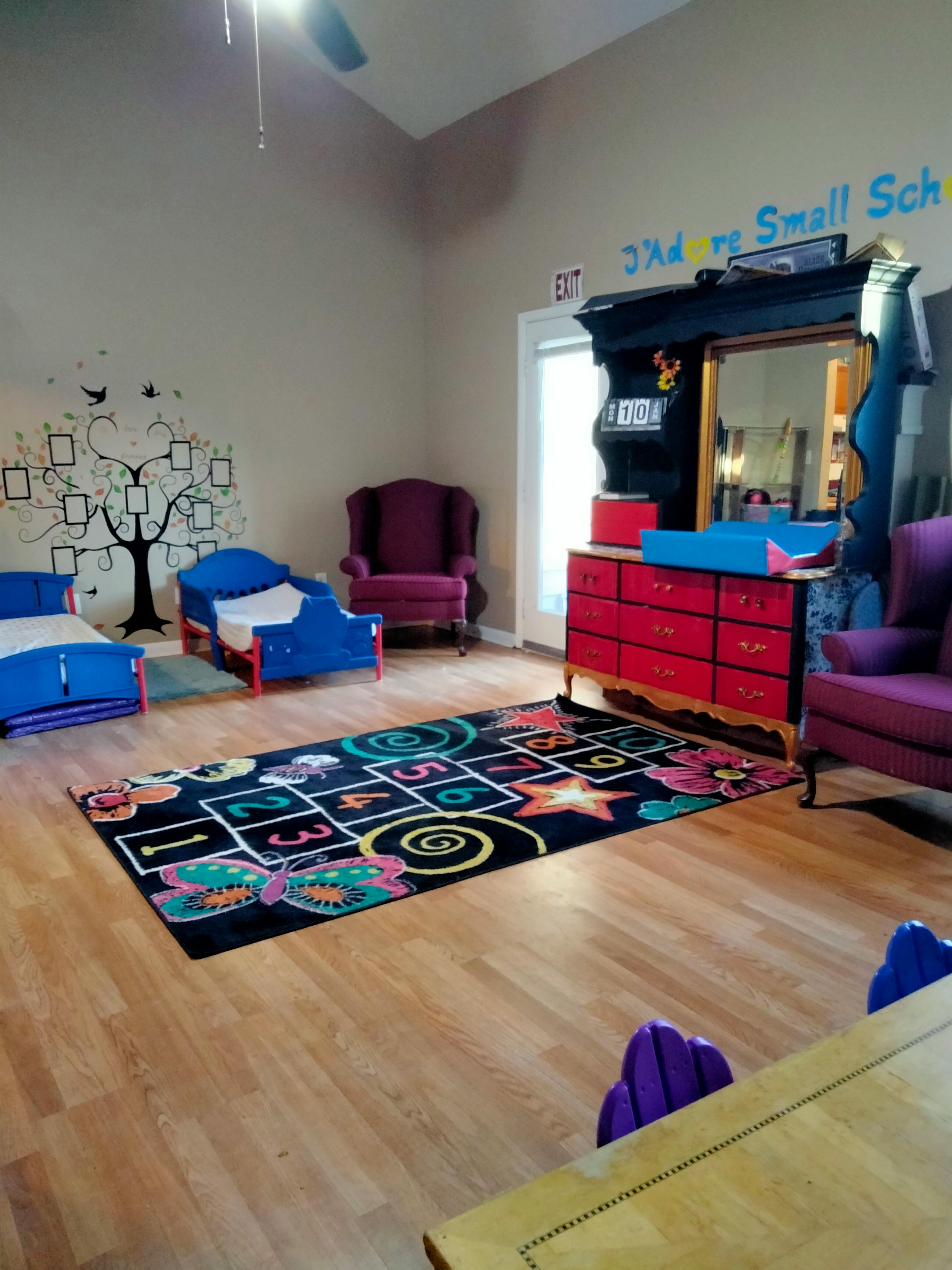 Playroom with two small beds, a hopscotch rug, and a red dresser