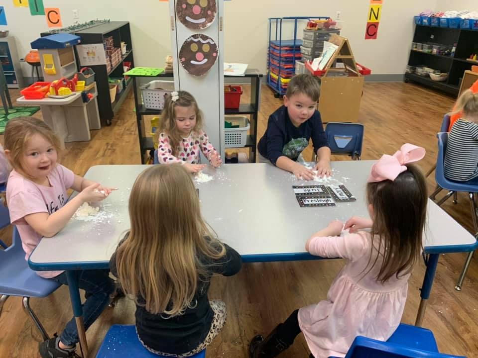 Children at a table playing with dough