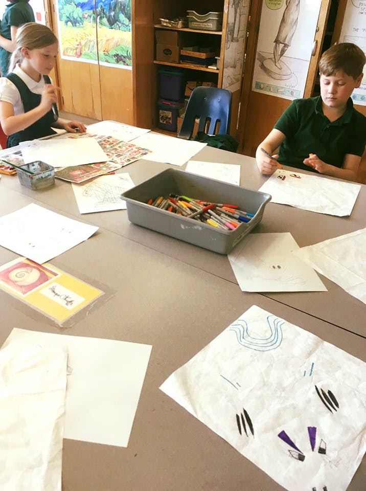 Two children drawing at a table in a classroom