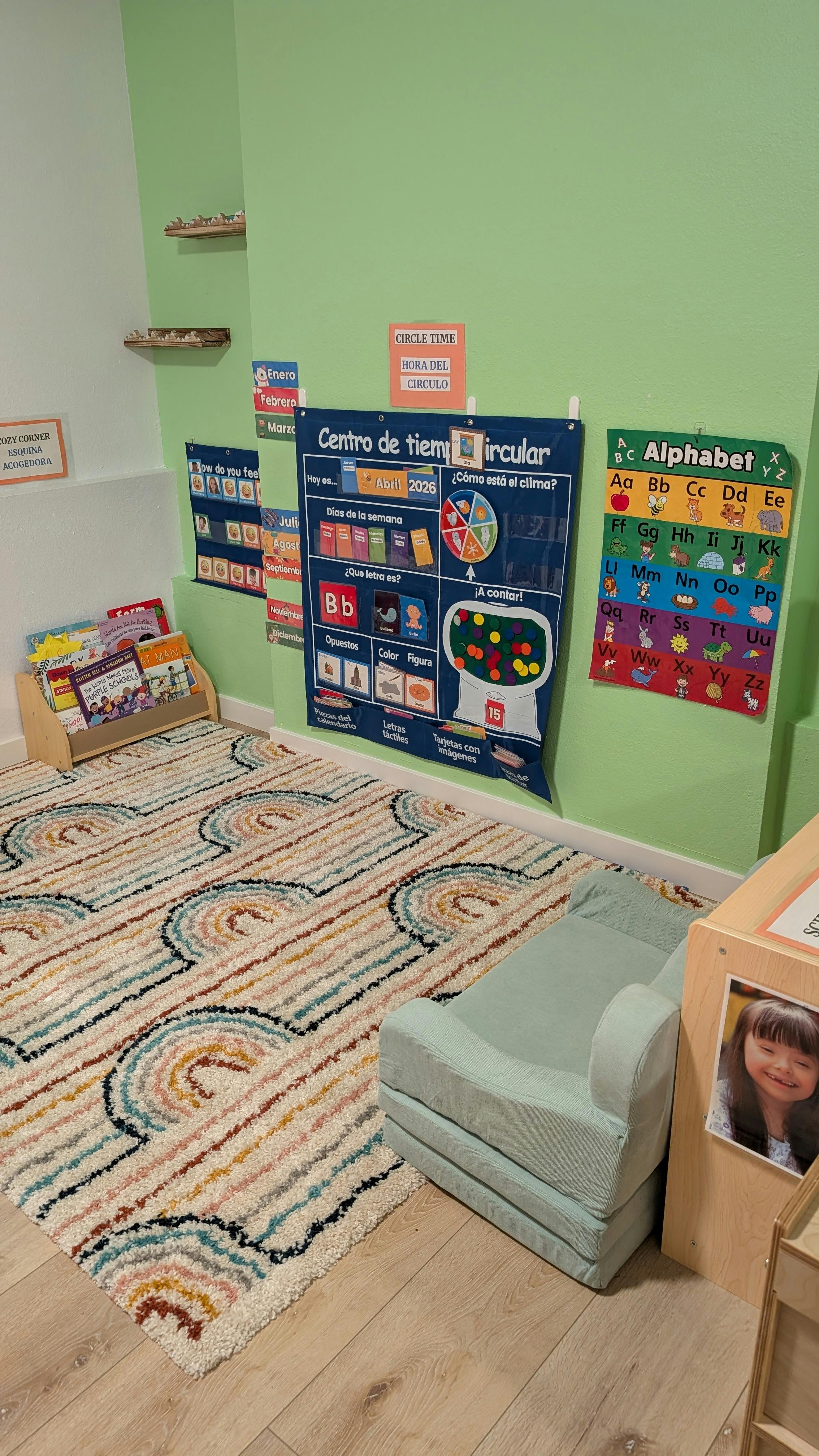 Children's classroom with rug, bookshelves, and wall charts in Spanish and English
