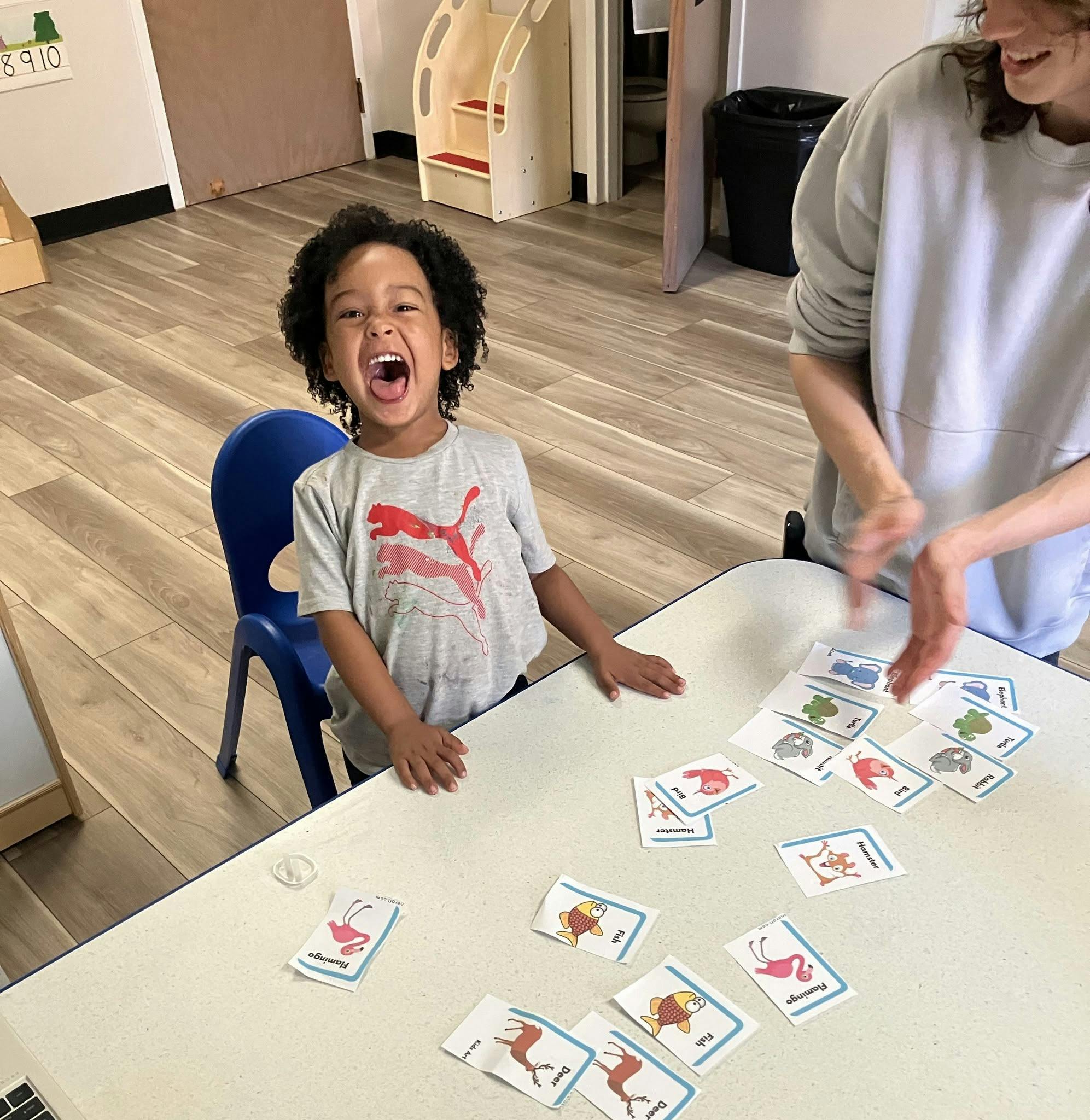 Child and person playing a matching card game at a table