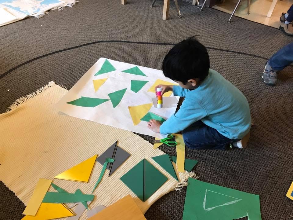 Child gluing paper shapes onto a large sheet