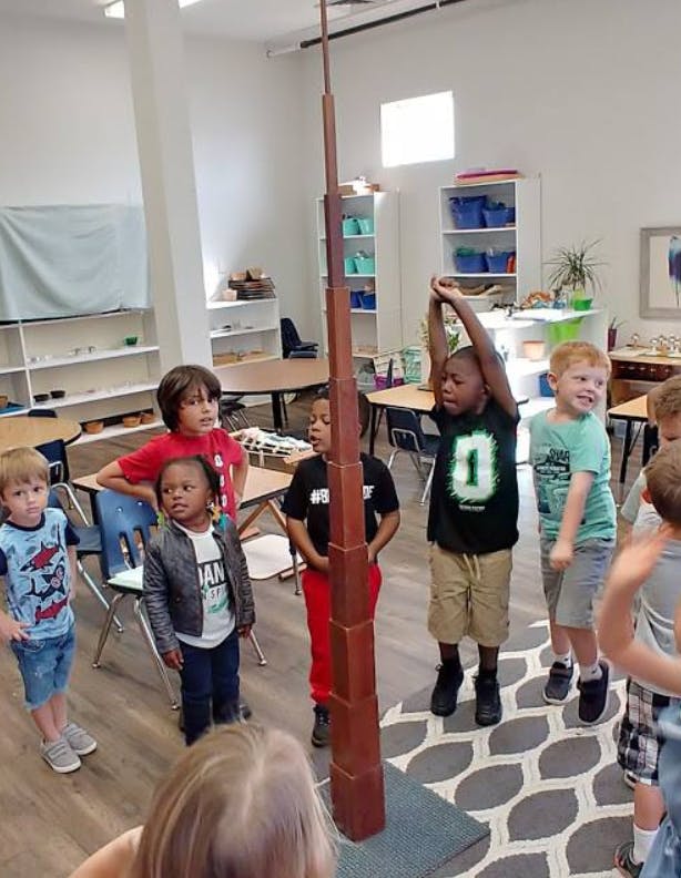 Children gathered around a tall wooden tower in a classroom