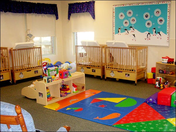 Nursery room with multiple cribs, playmat, and toys