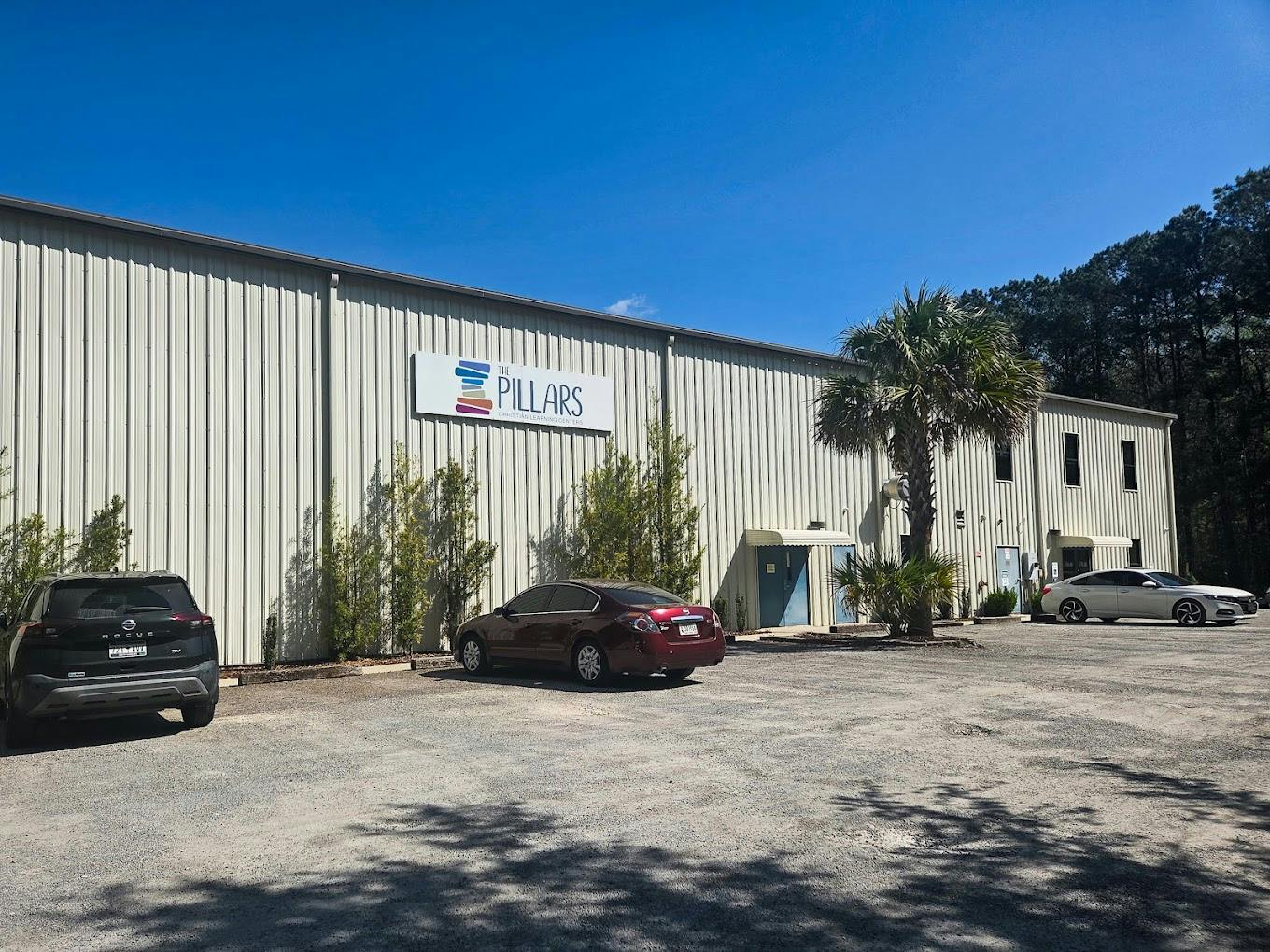 Exterior of The Pillars Christian Learning Centers building with parked cars