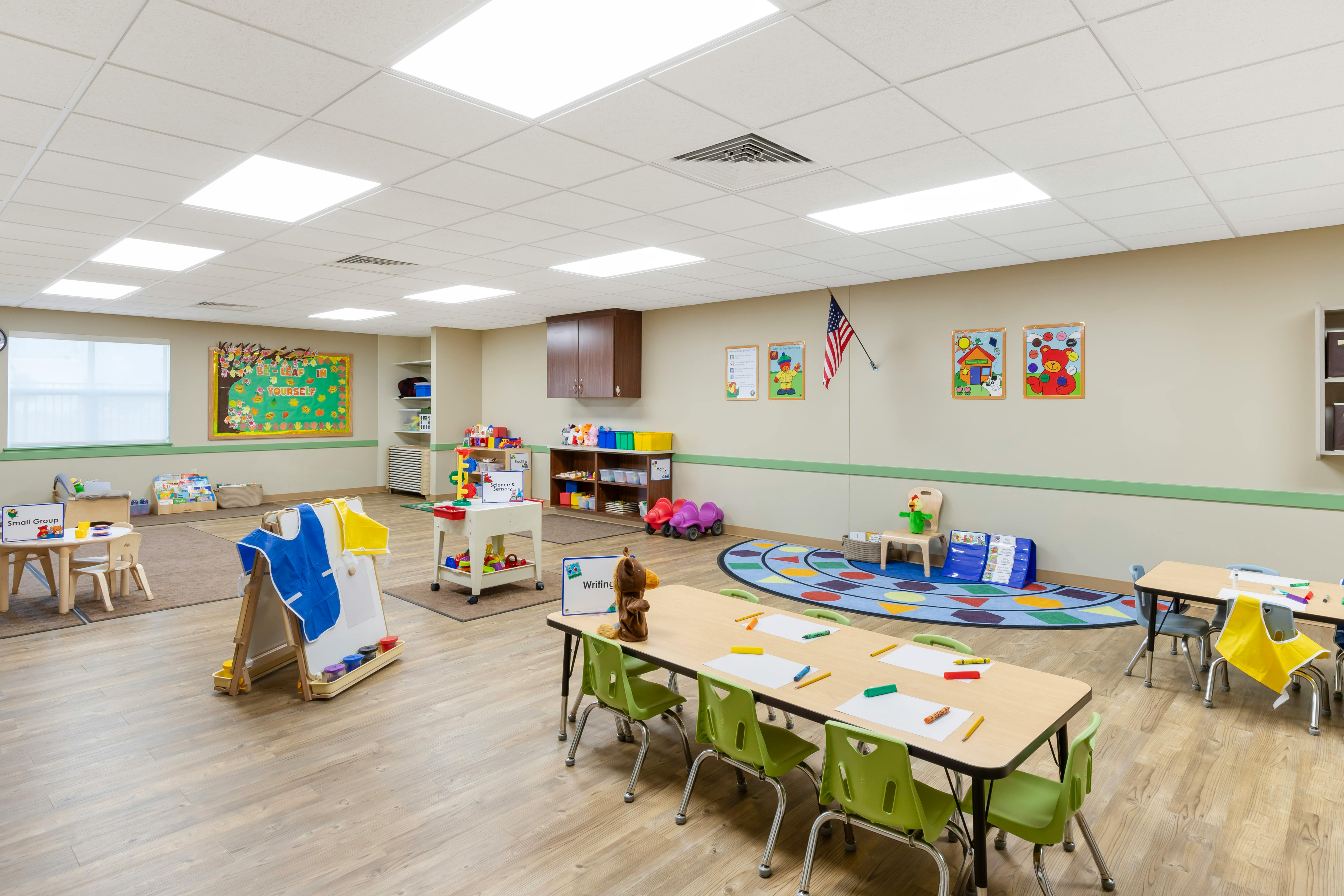 An empty early childhood classroom with multiple tables and chairs