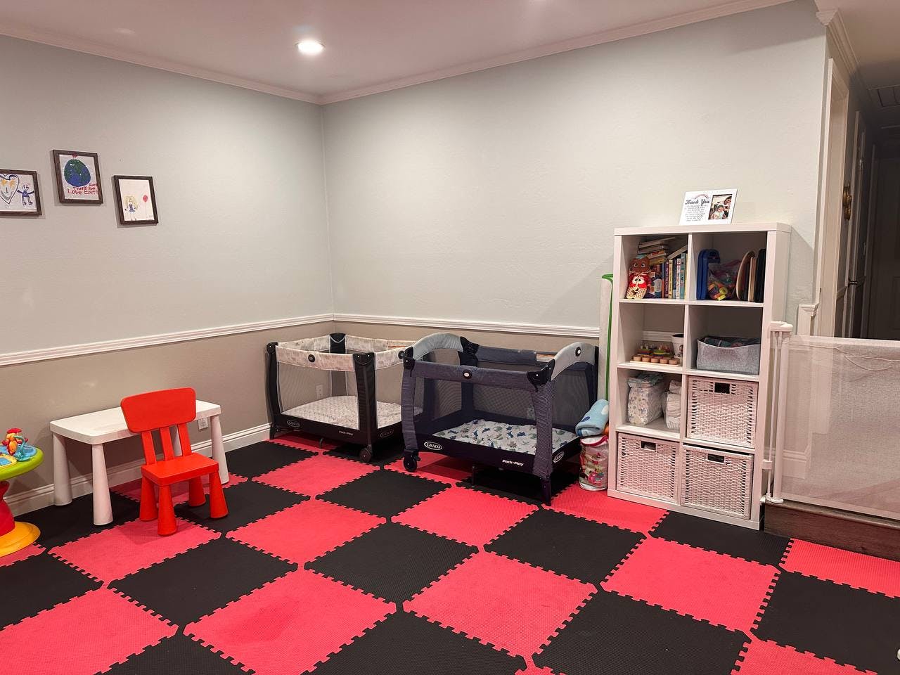 Playroom with red and black checkered floor, two cribs, and a bookshelf