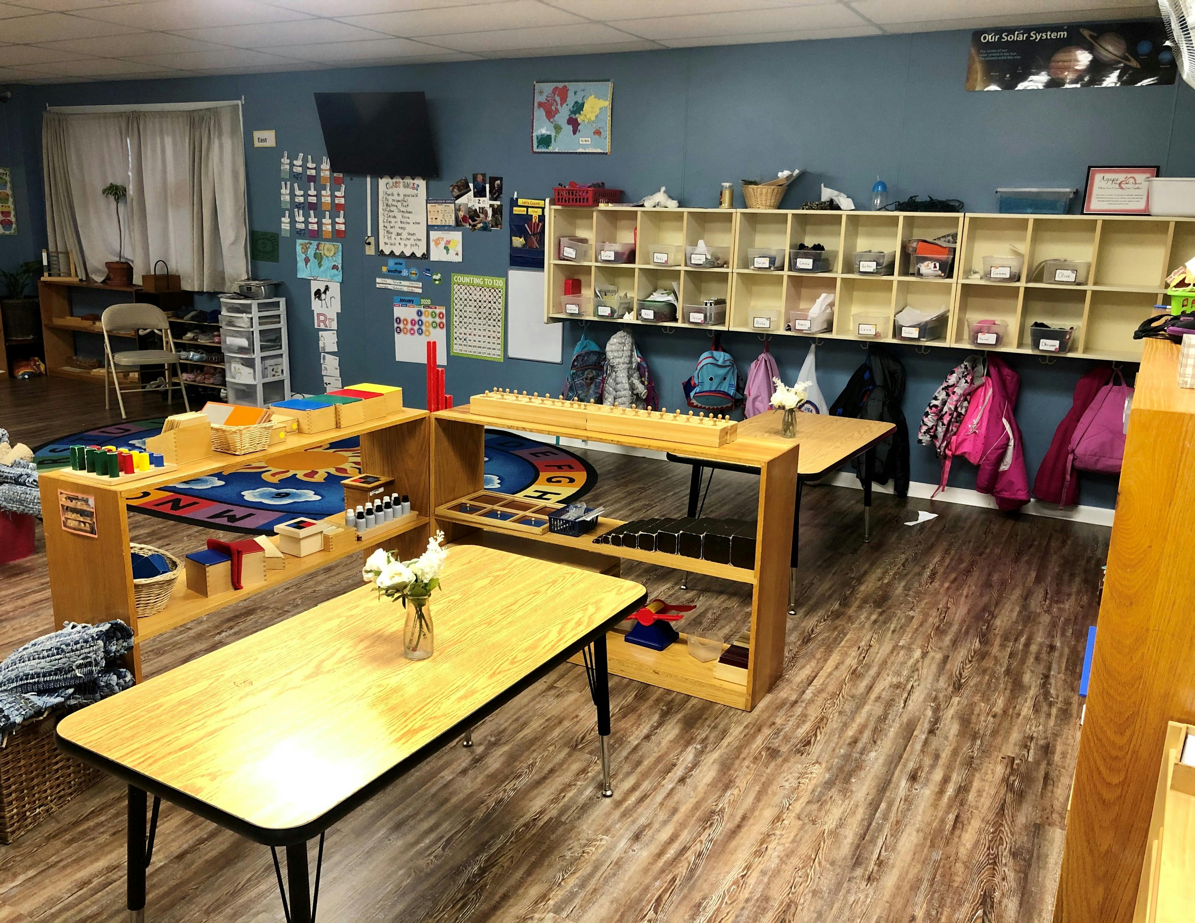 Classroom with tables, shelves, and coats hanging