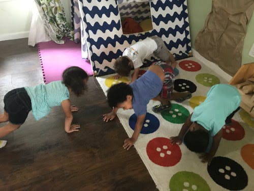 Four children playing on a rug with colorful circles