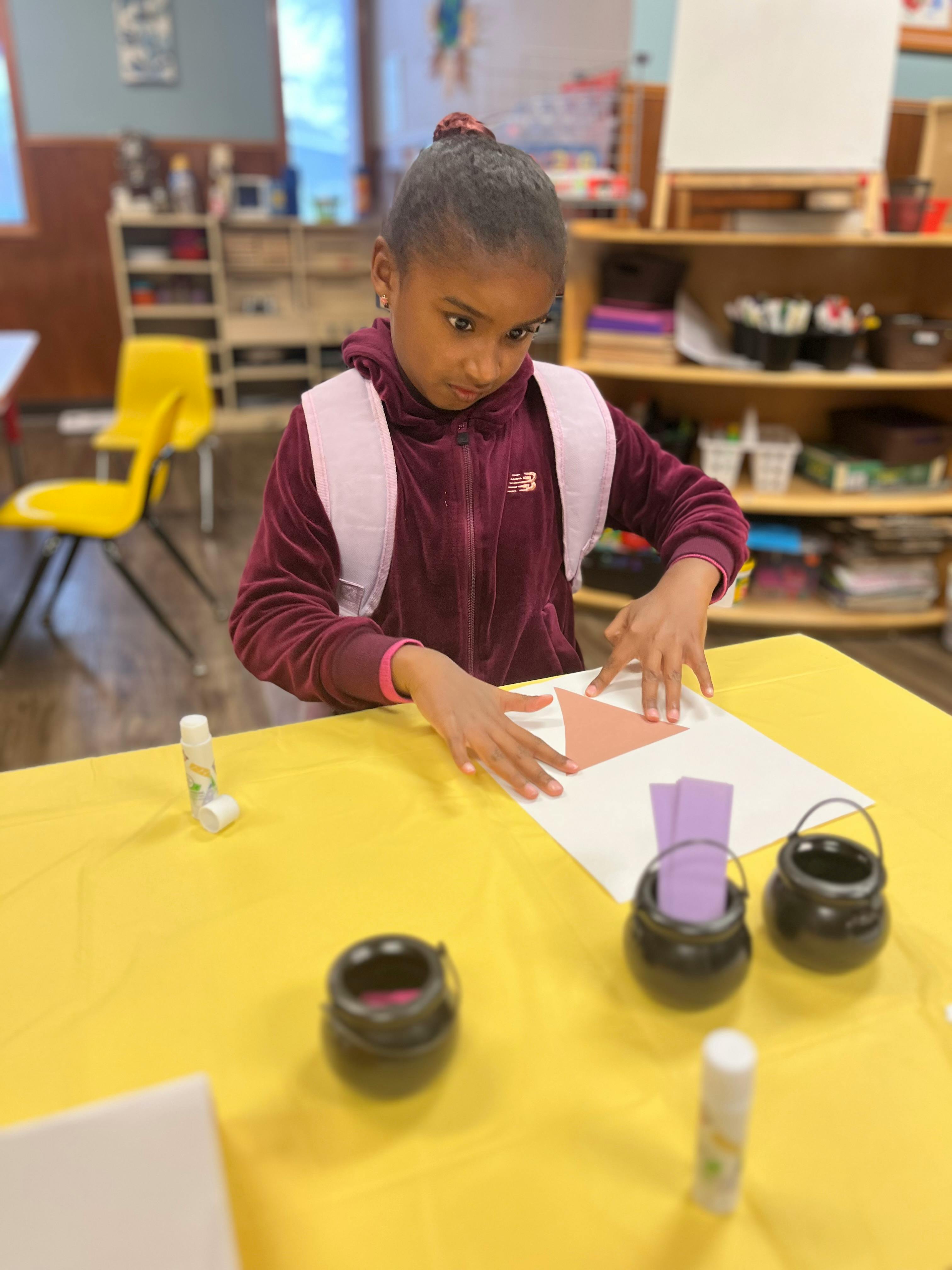 Child doing an art project at a table in a classroom
