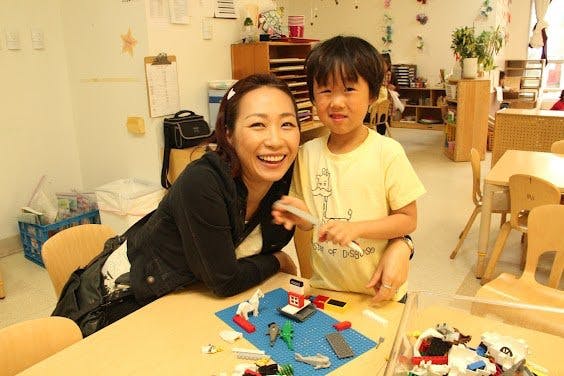 Person and child at a table with toys in a classroom