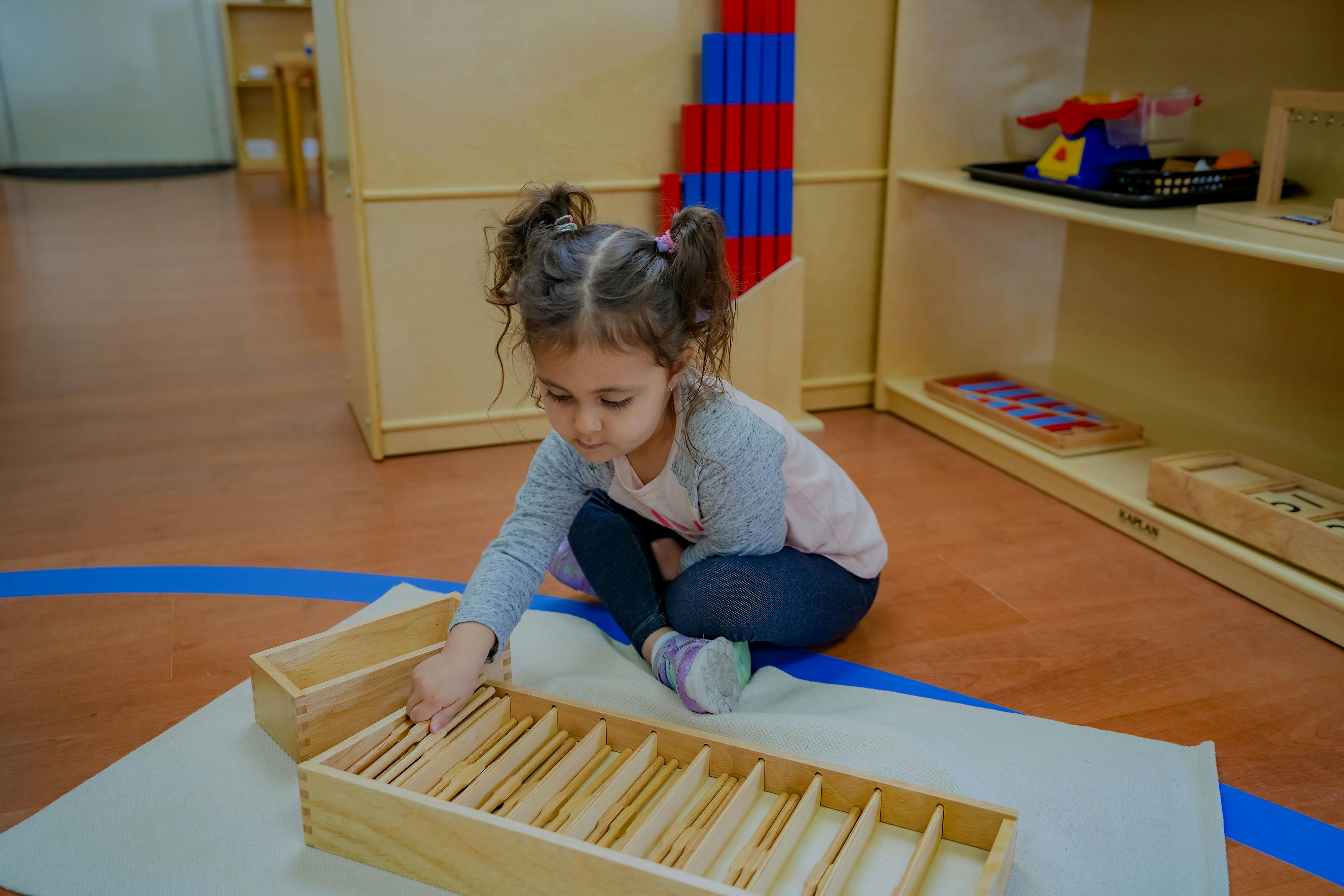 Child playing with wooden blocks on the floor in a classroom
