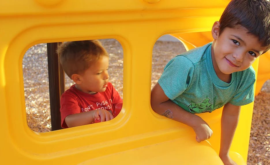 Two children in a yellow play structure