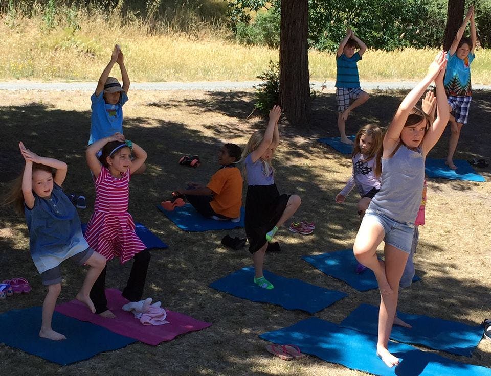 Children doing yoga outdoors on mats