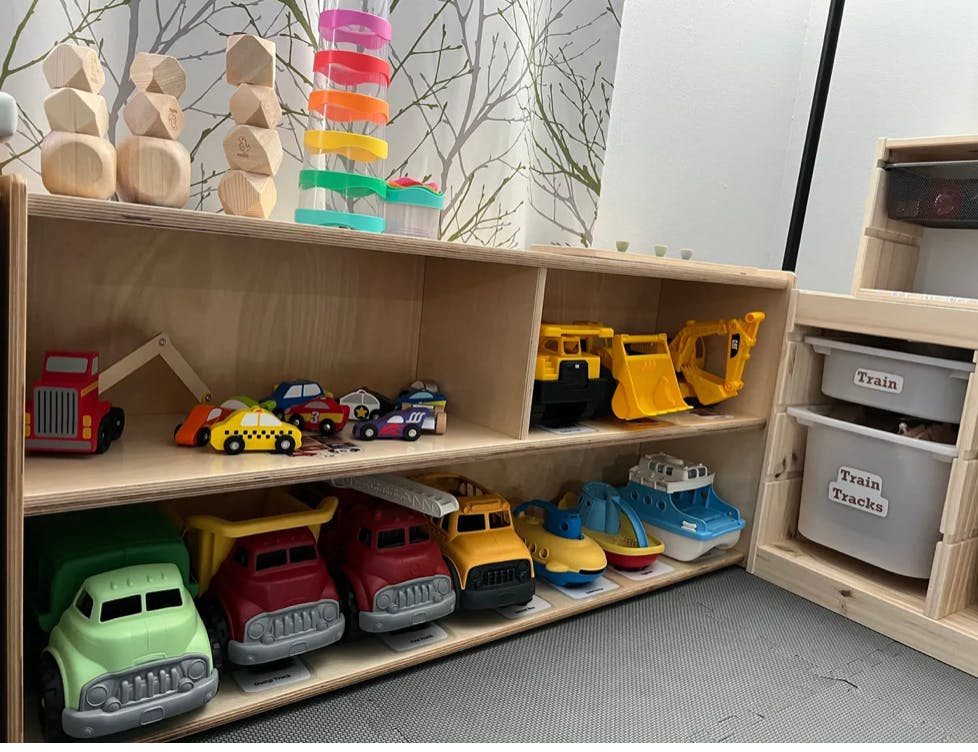 Wooden shelves with toy cars, trucks, and building blocks
