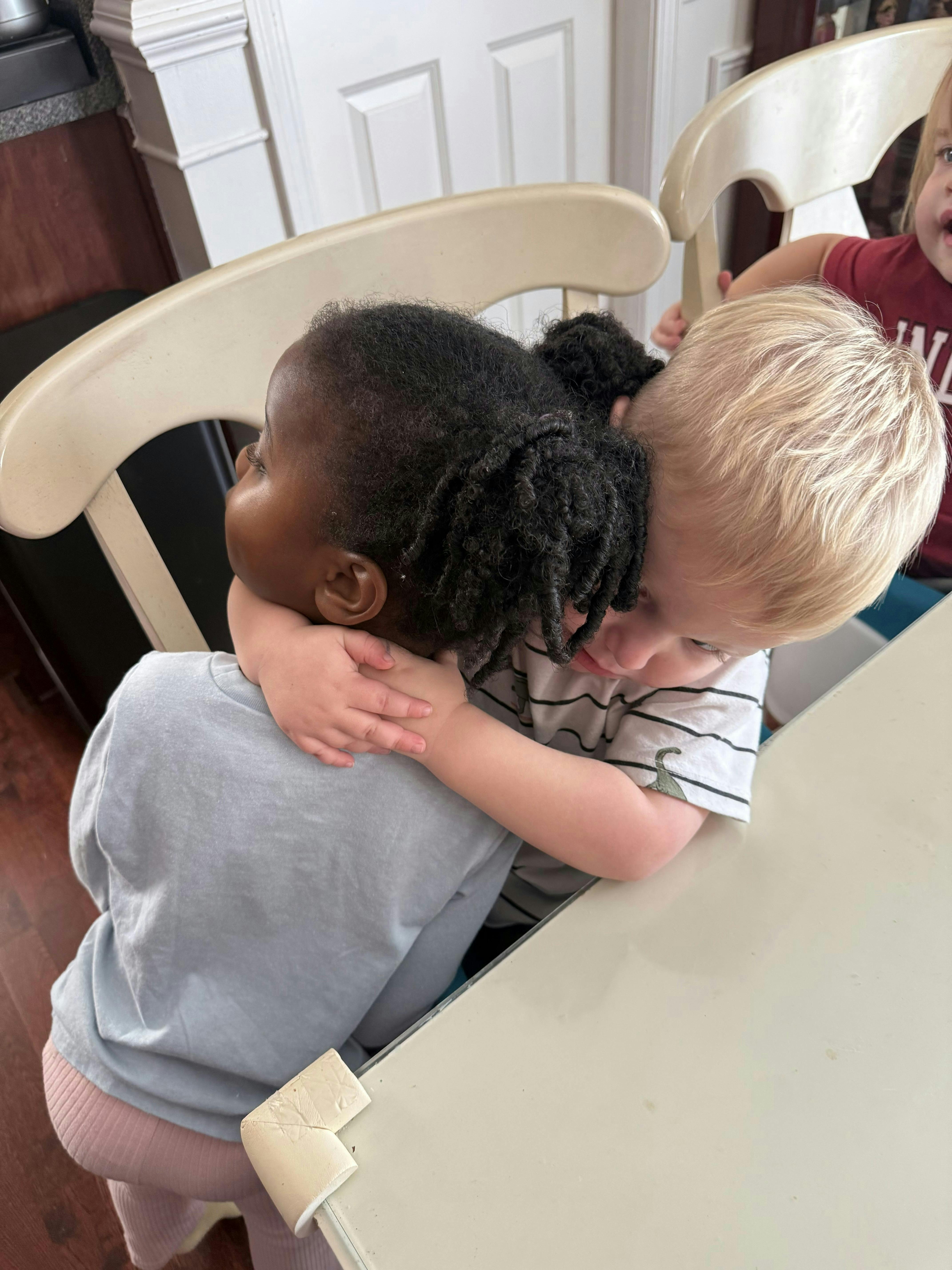 Two children hugging at a table