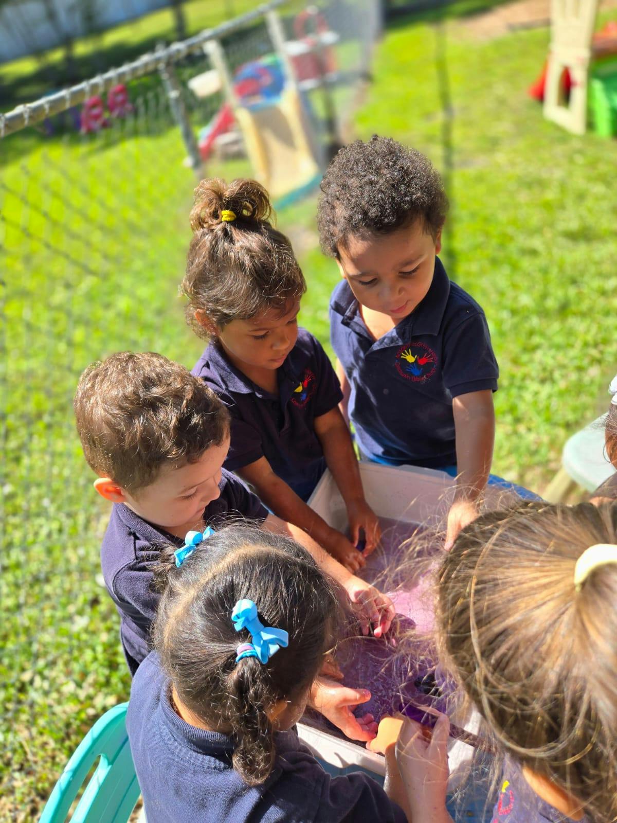 Children gathered around a table, playing with a purple substance