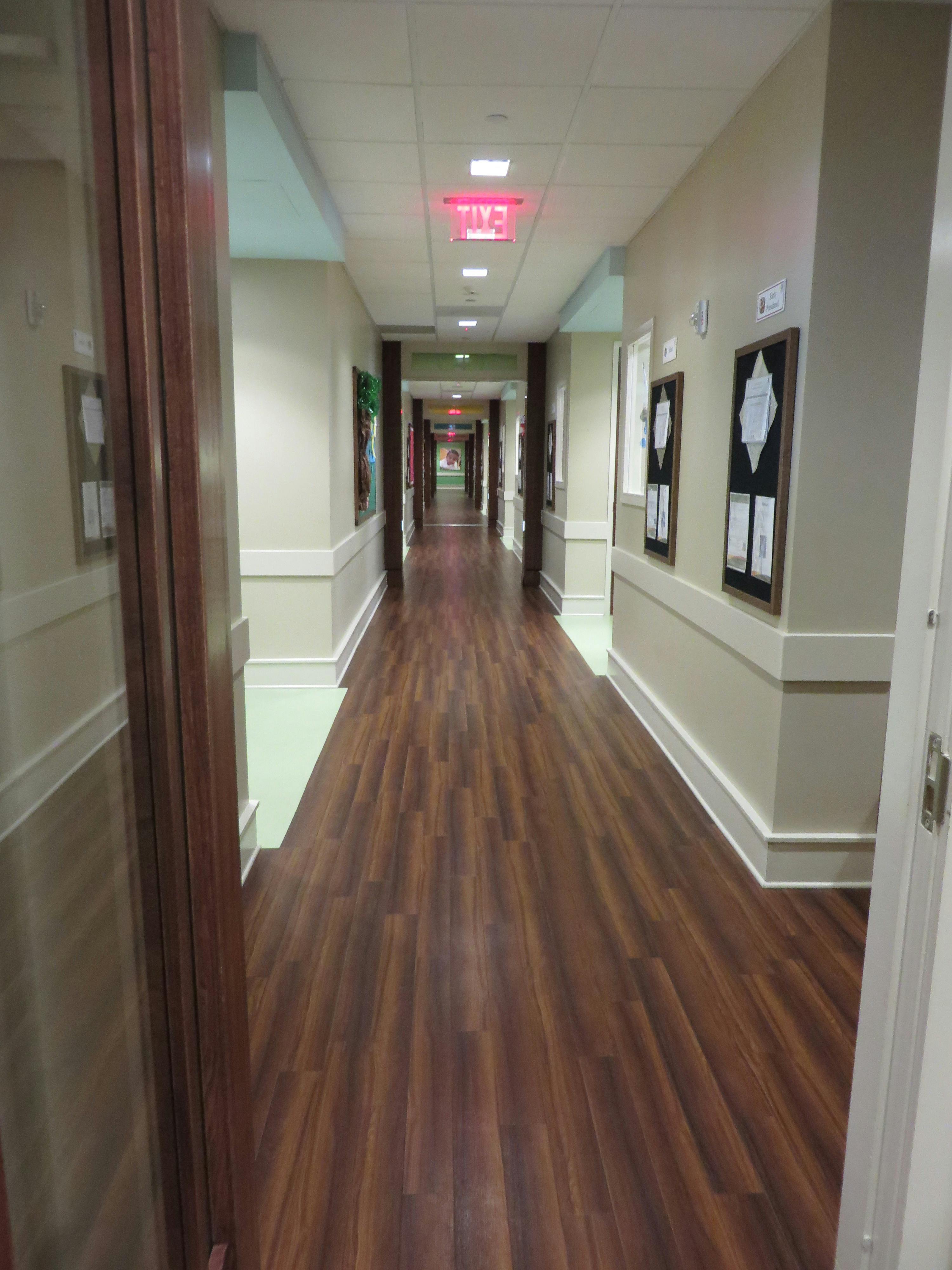 Long hallway with wood floor and an exit sign