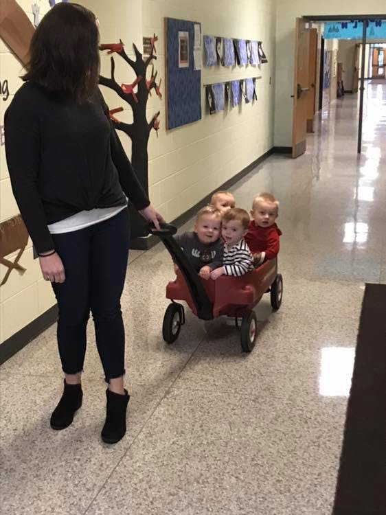 Person pulling a wagon with four children in a hallway