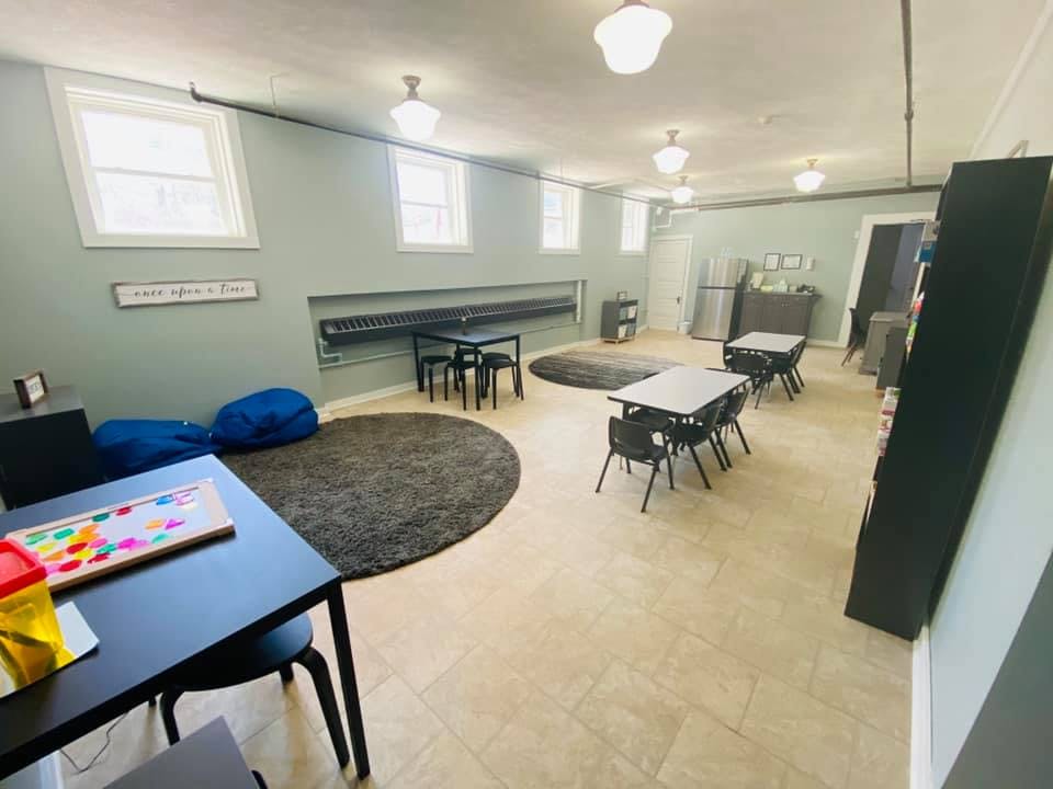 Classroom with small tables and chairs, bean bags, and round rugs