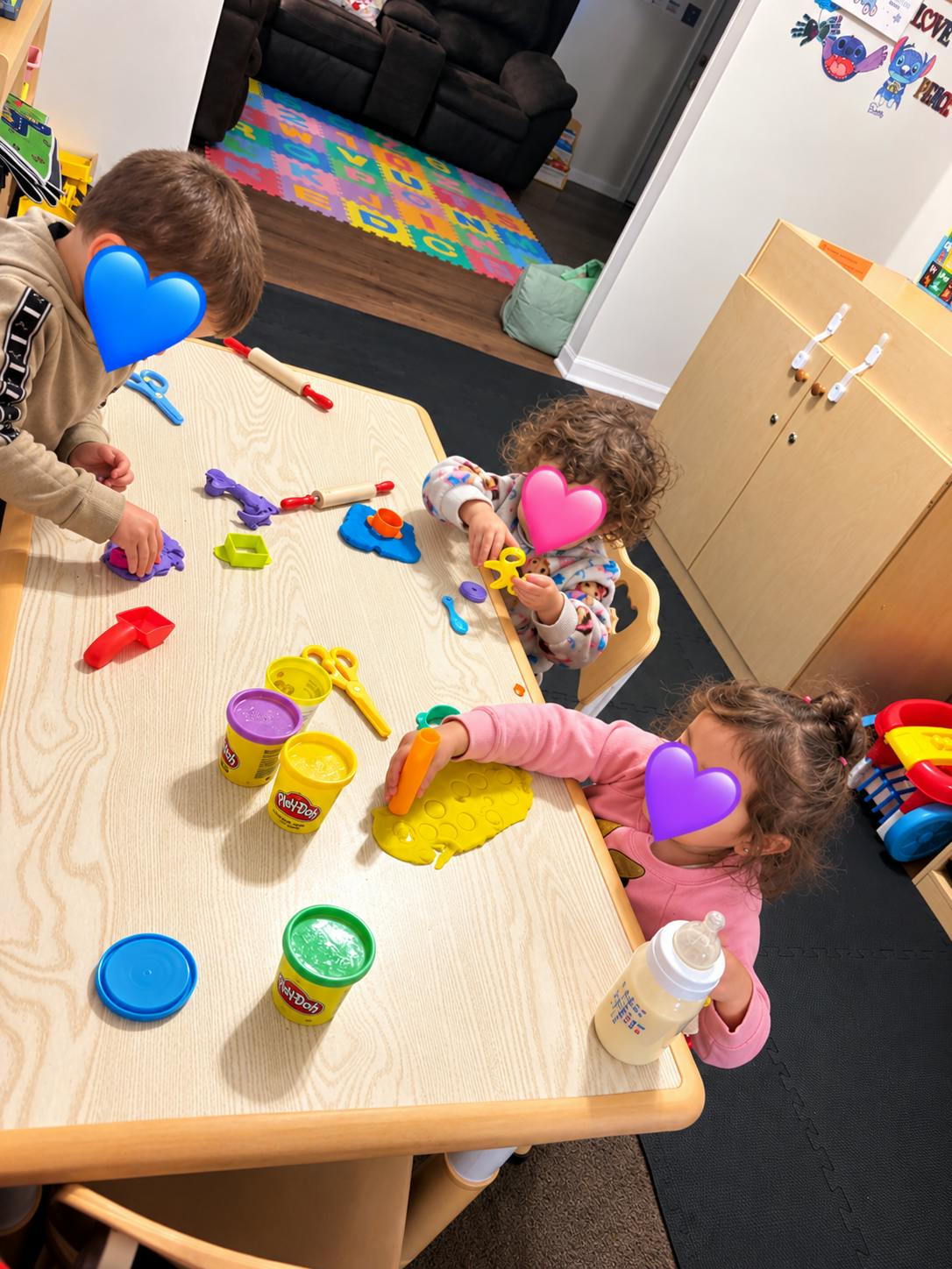 Three children playing with modeling clay at a table