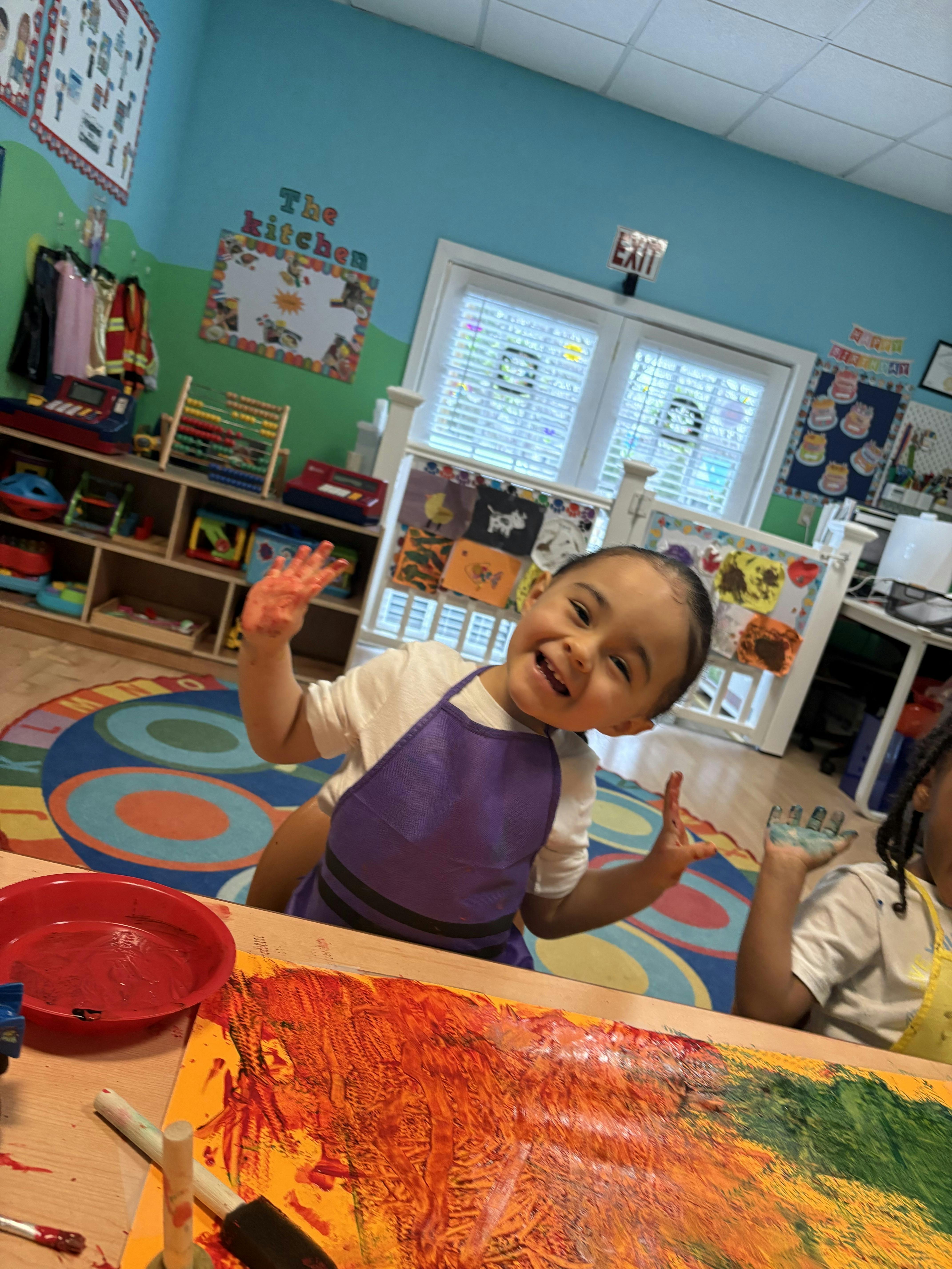 Child with painted hands and a purple apron