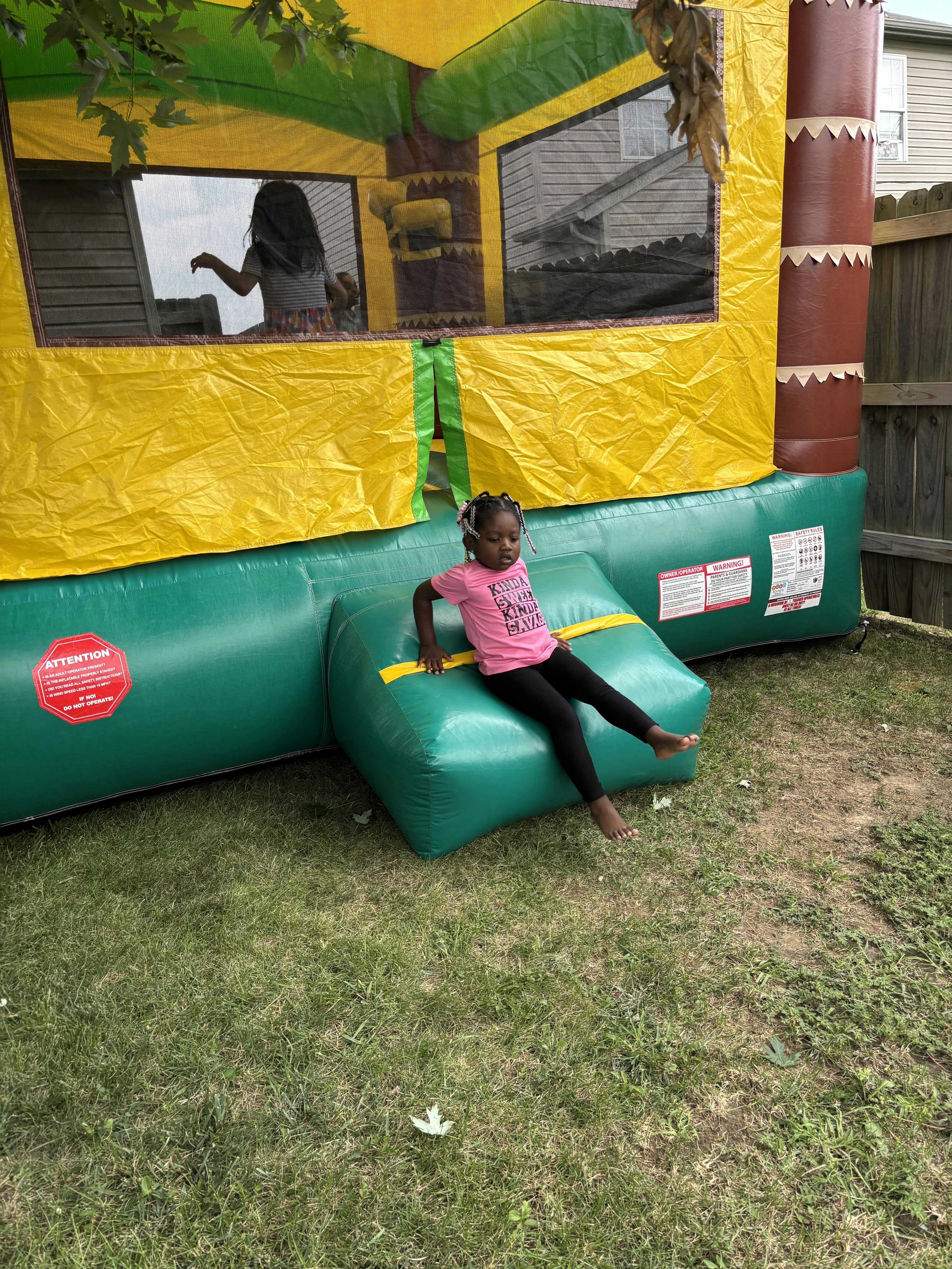Child sitting on the inflatable entrance of a bounce house