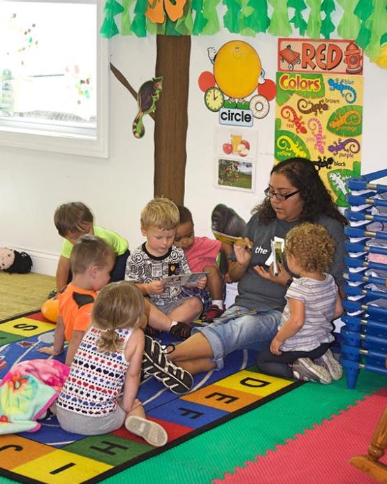 Person reading to a group of children in a classroom