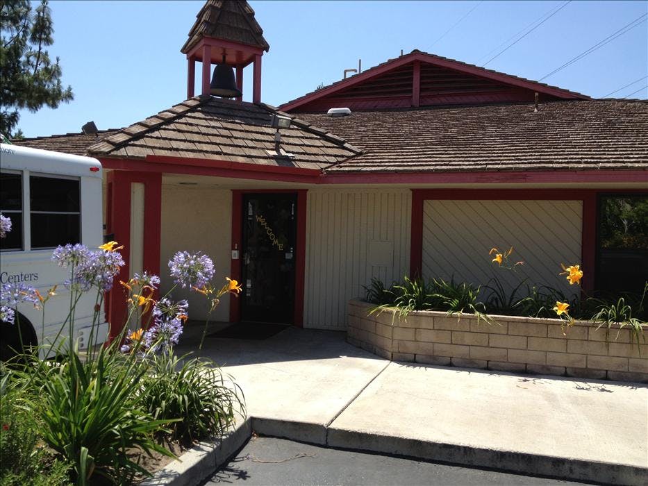 A building with a bell tower, a school bus, and flowers