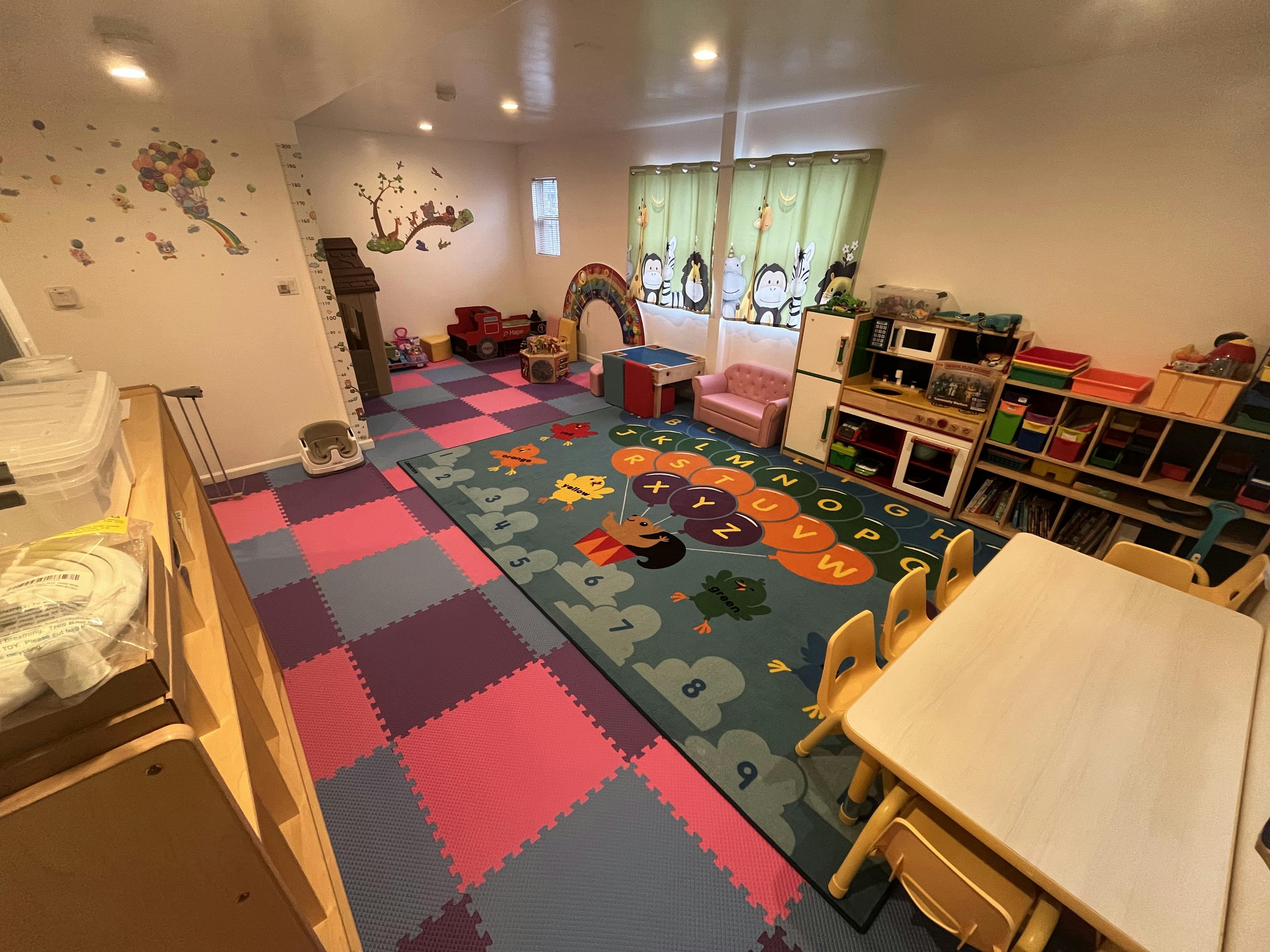 Children's playroom with colorful floor mats, a patterned rug, and various toys