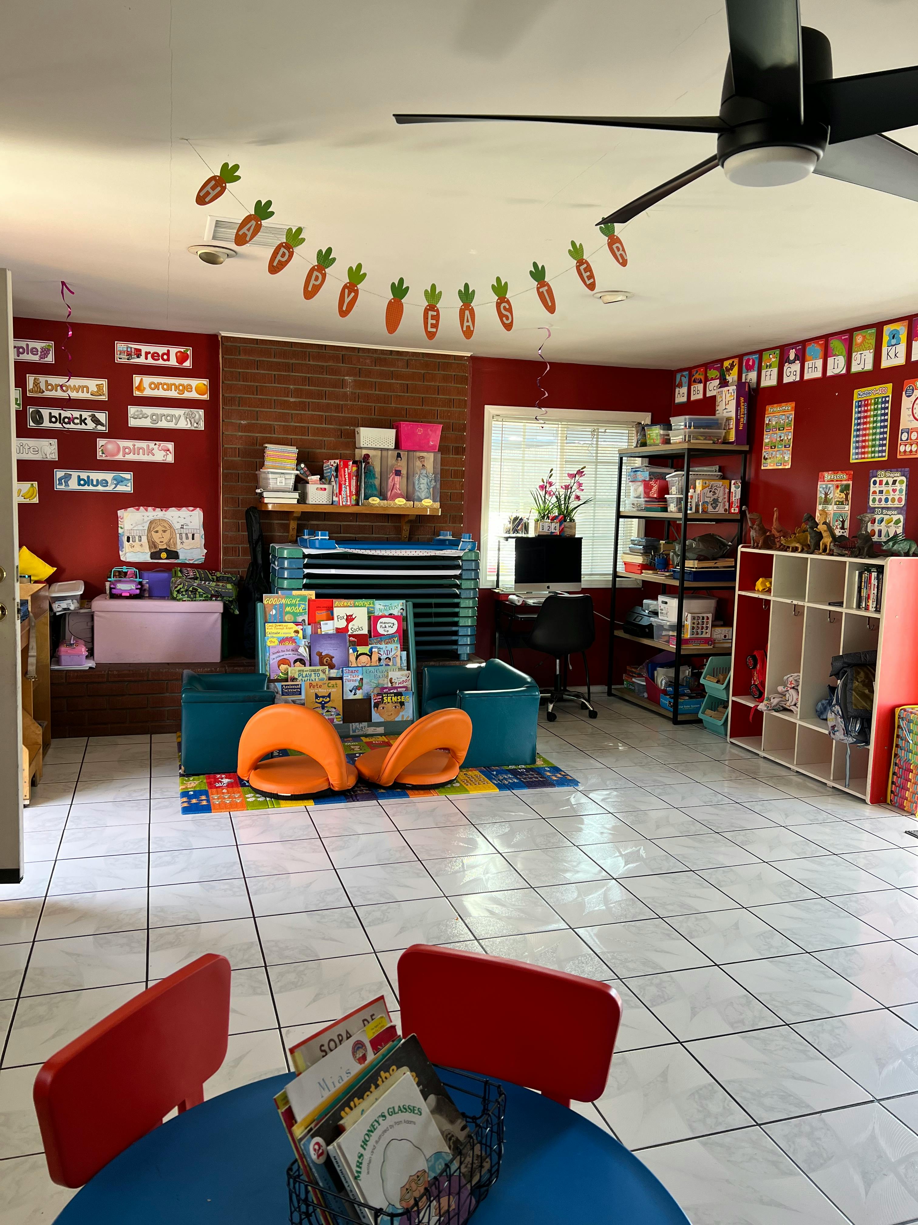 Classroom with red walls, shelves, and a small blue table with red chairs