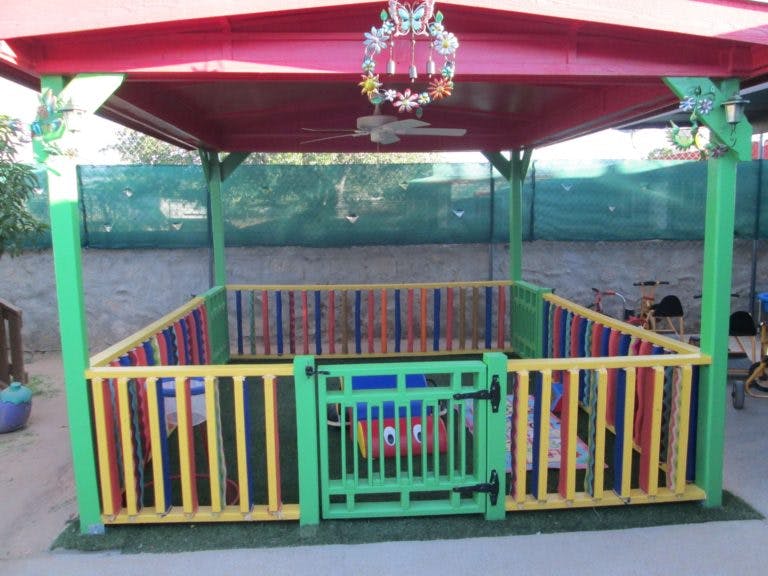 Colorful fenced play area under a red canopy