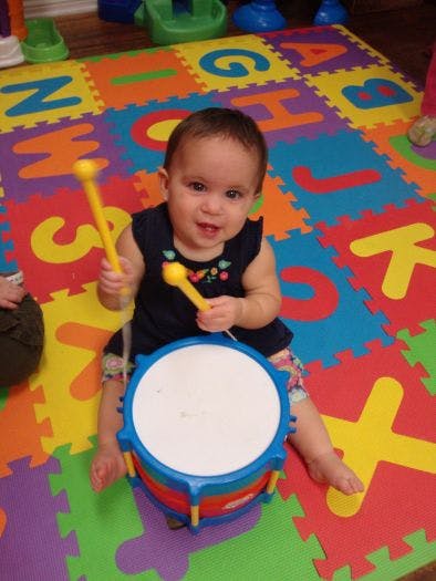 Child playing a drum with mallets on an alphabet mat