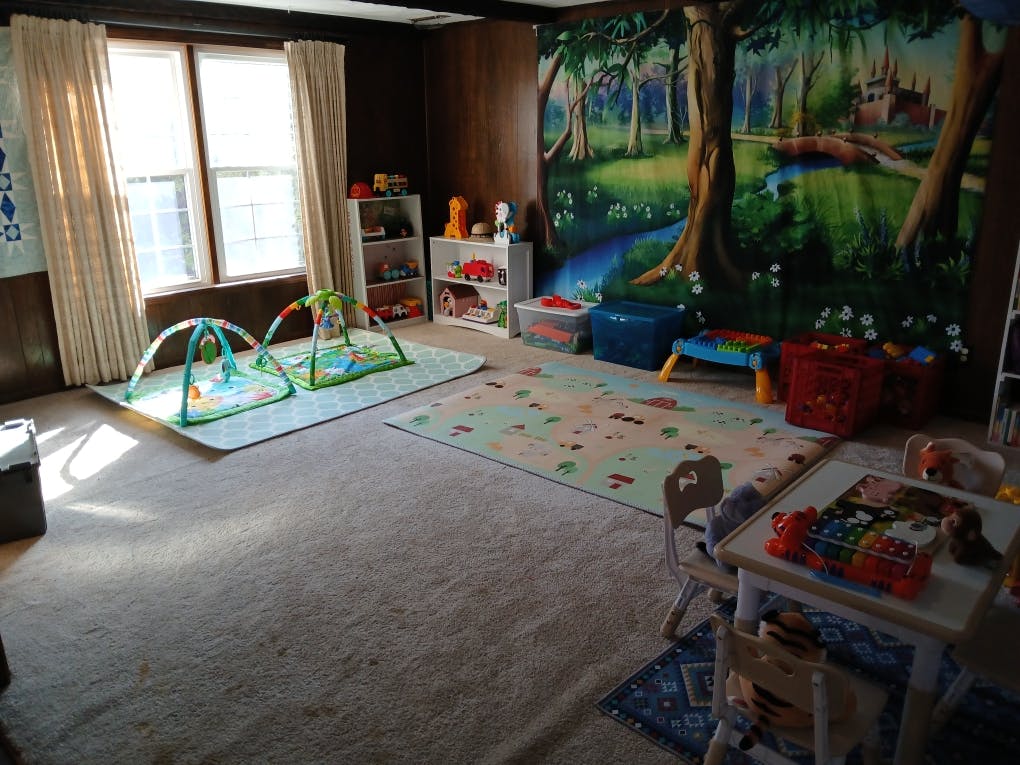 Playroom with playmats, toys, and a forest mural