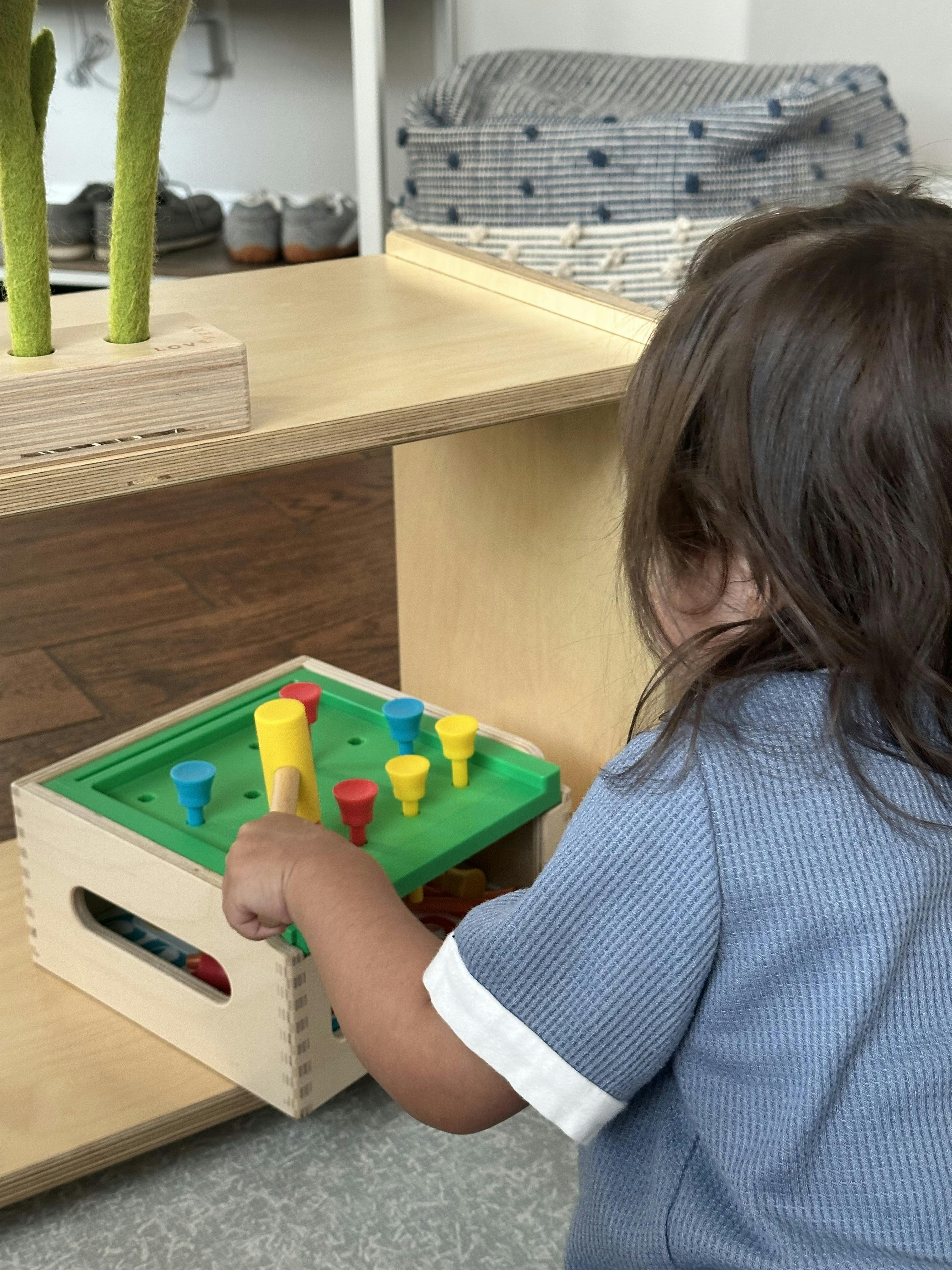 Child playing with a wooden pounding toy