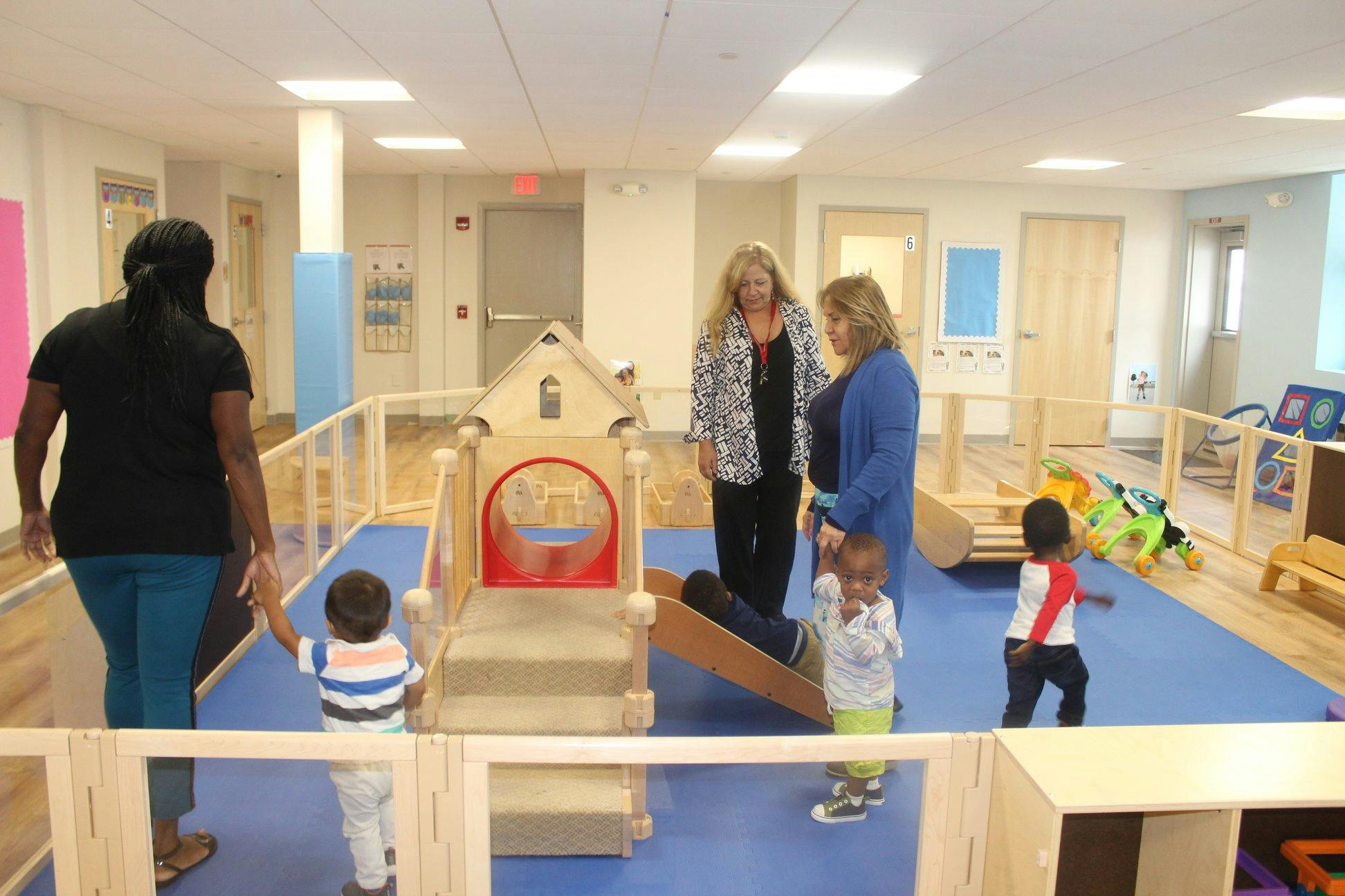 Adults and children in a play area with a small play structure