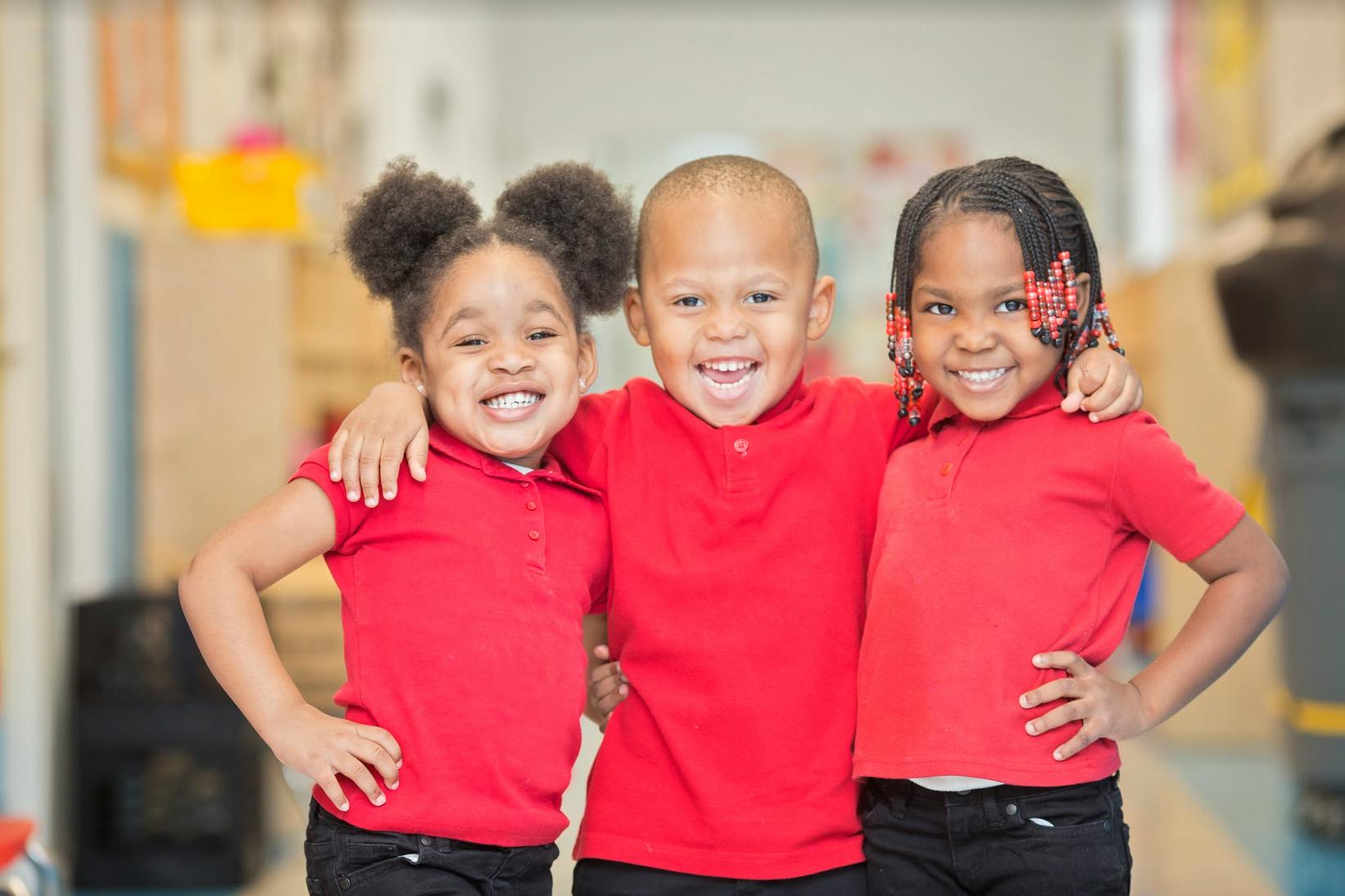 Three children in red shirts with arms around each other