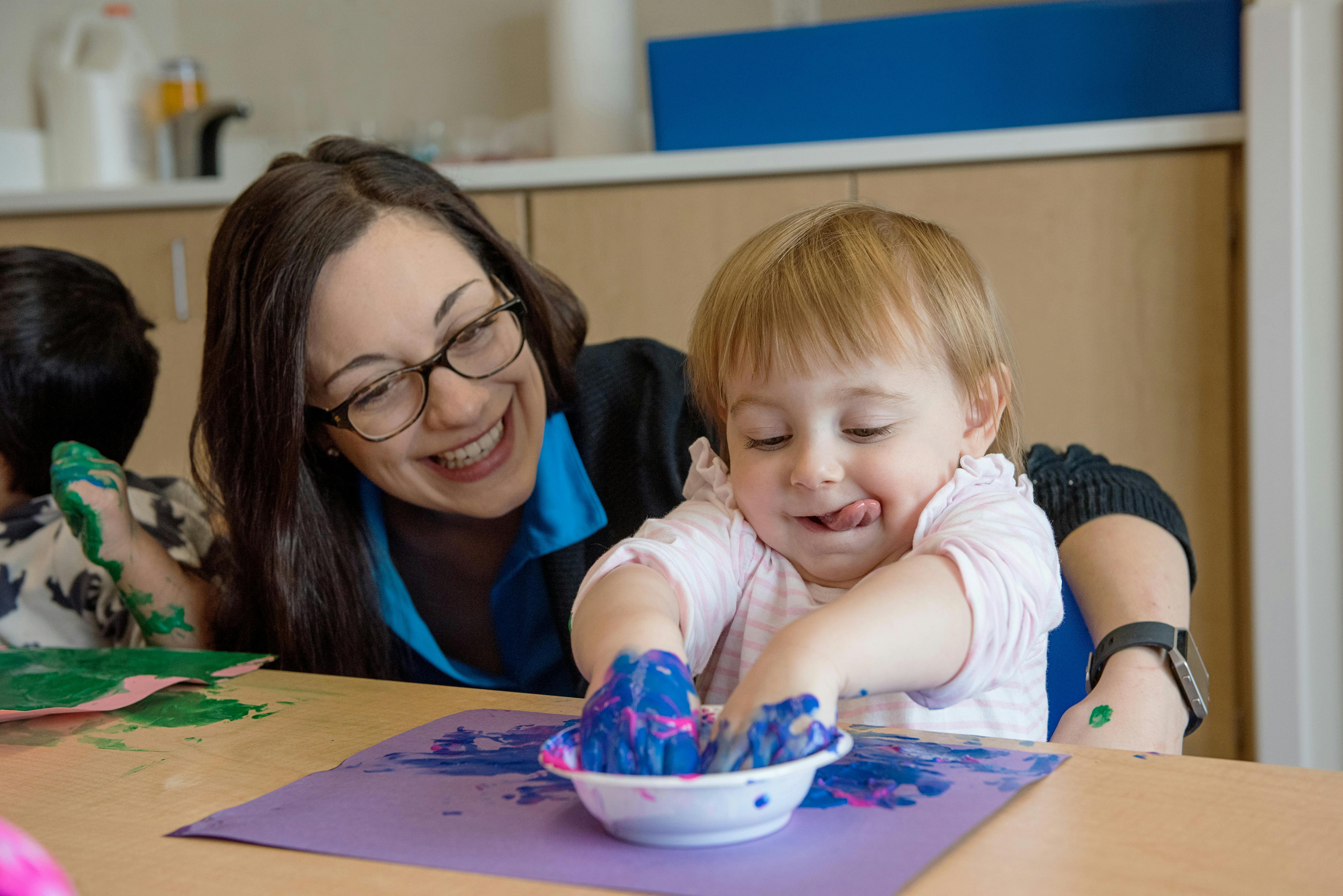 Adult and child finger painting with blue and pink paint