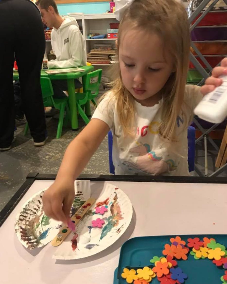 Child decorating a paper plate craft with craft supplies