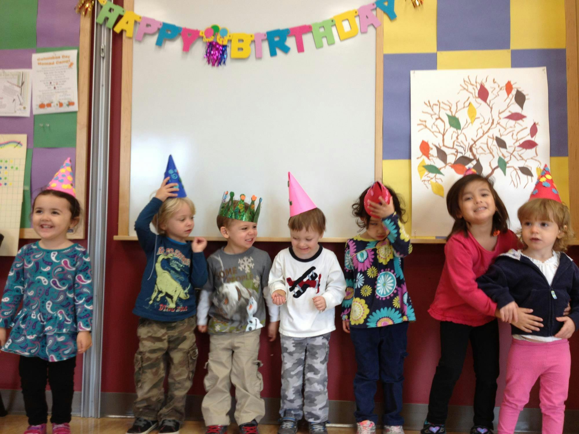 Children wearing party hats and crowns standing in a line