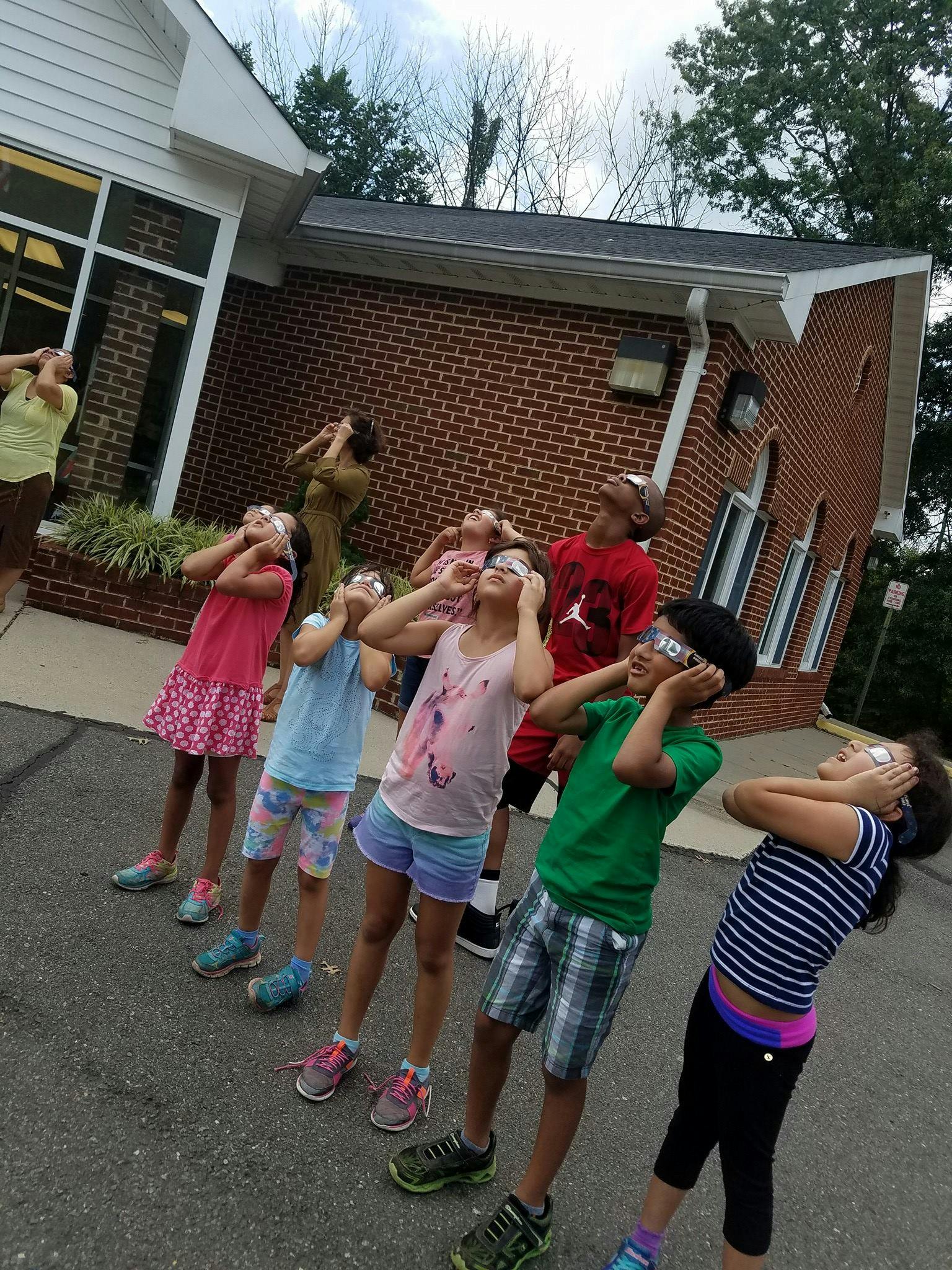 People and children looking up at the sky with protective glasses