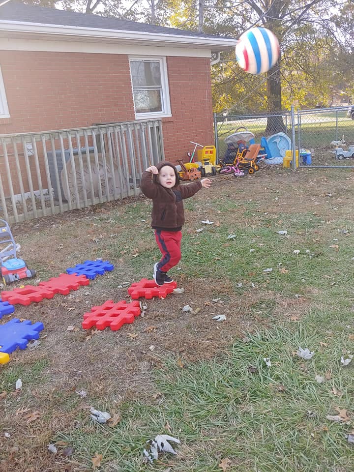 Child throwing a ball in a yard