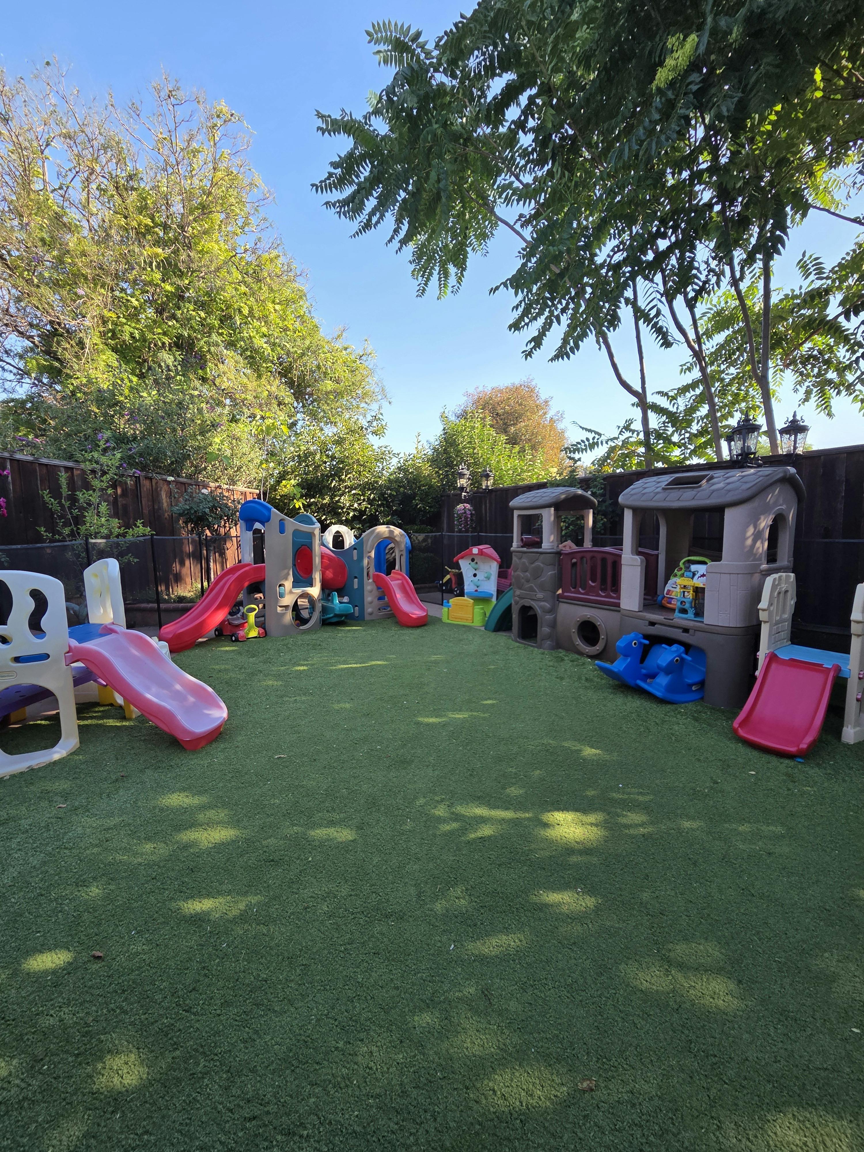 Children's playground with multiple plastic slides and play structures on green turf