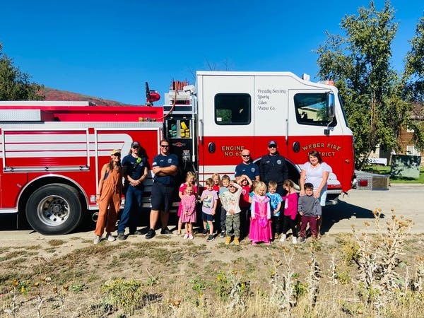 Adults and children posing in front of a fire truck
