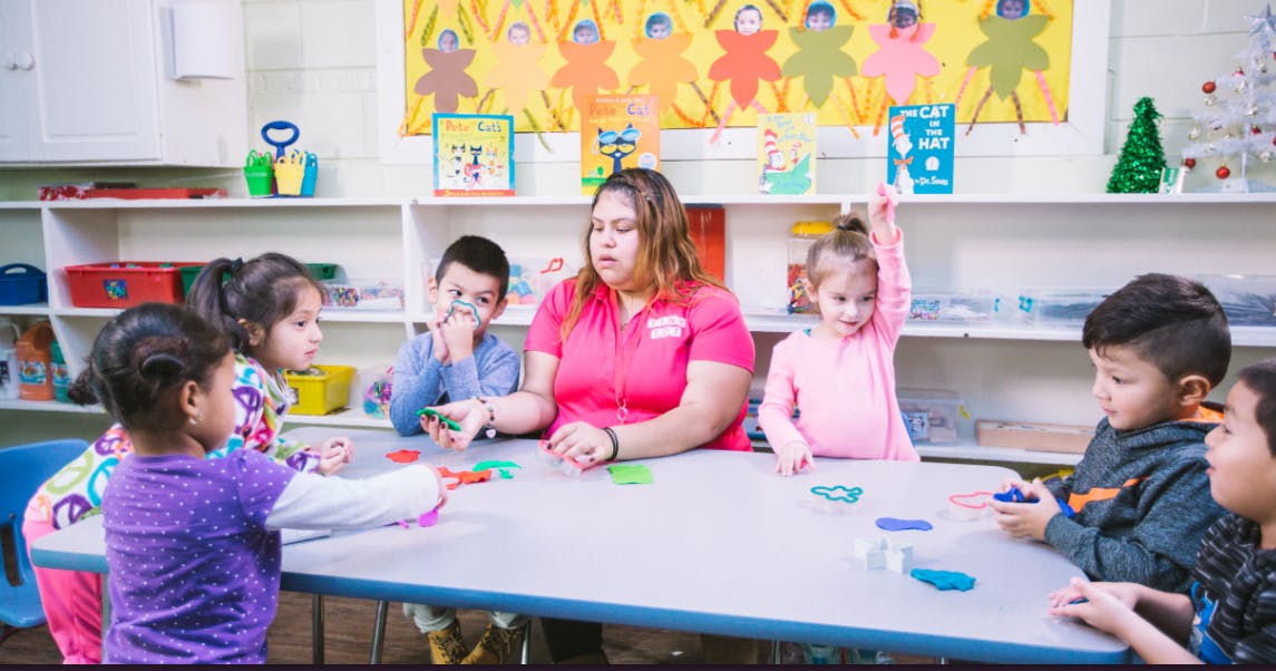 Adult and multiple children sitting at a table in a classroom